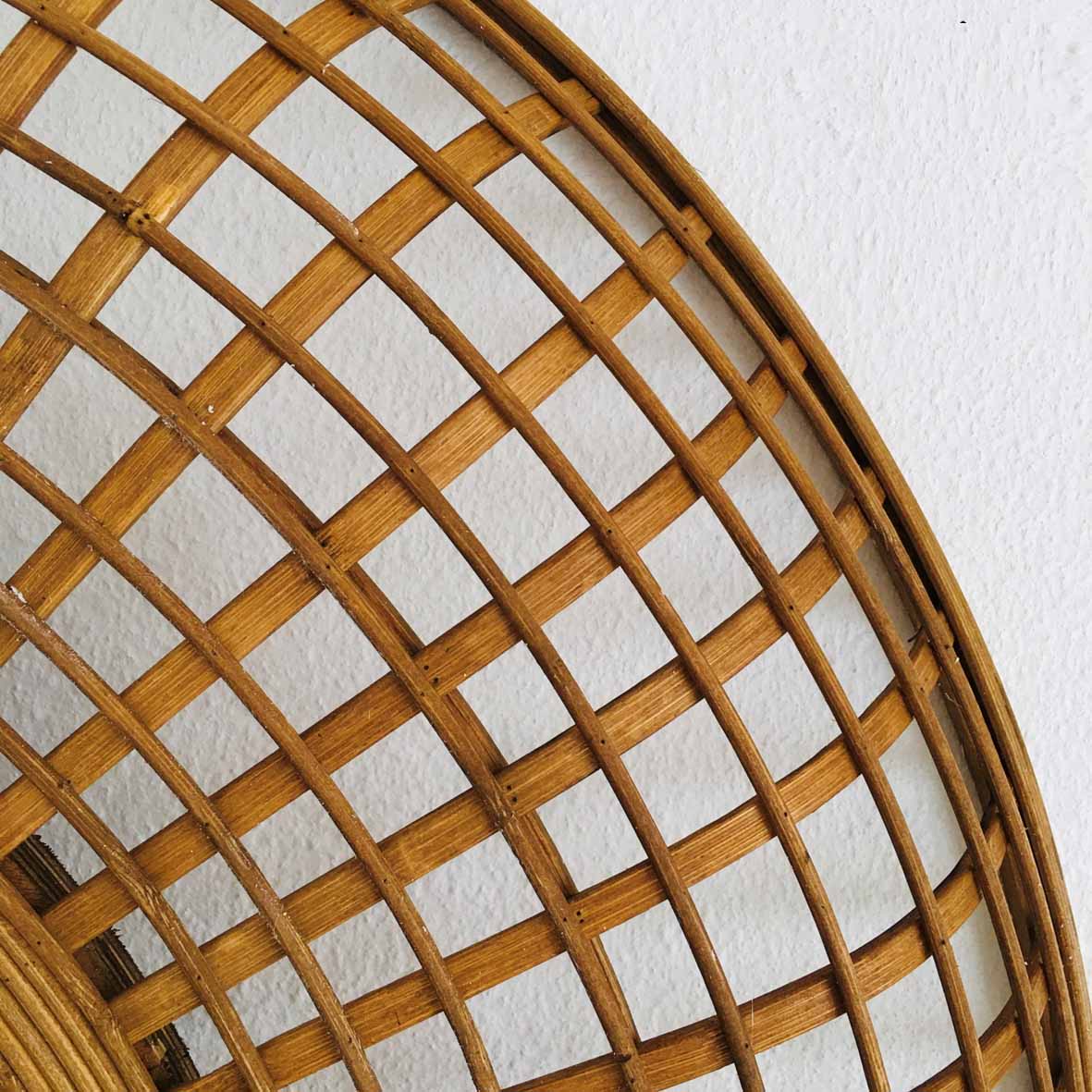 Grelha circular de madeira com padrão entrelaçado em parede branca