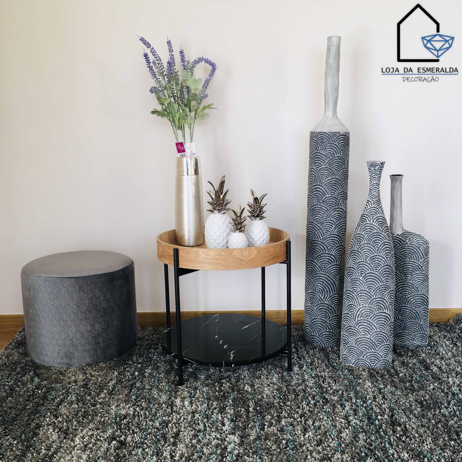 Conjunto decorativo com pufe, mesa redonda, abacaxis decorativos, jarro com flores e vasos altos com padrão preto e branco