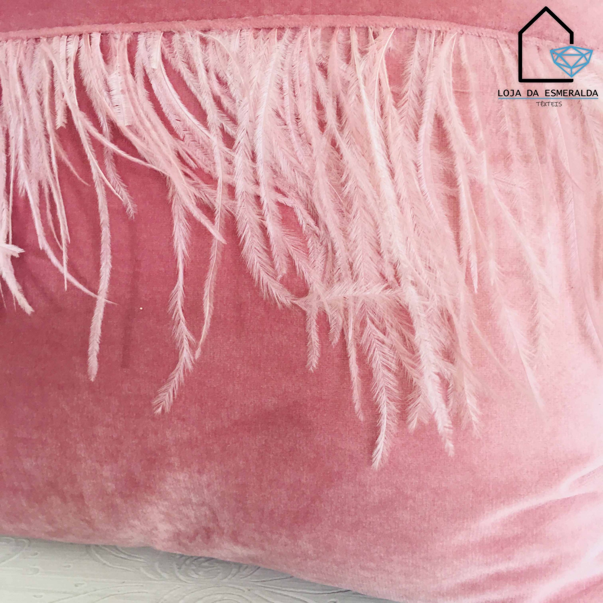 Almofada rosa de veludo com franjas de penas e logótipo Loja da Esmeralda