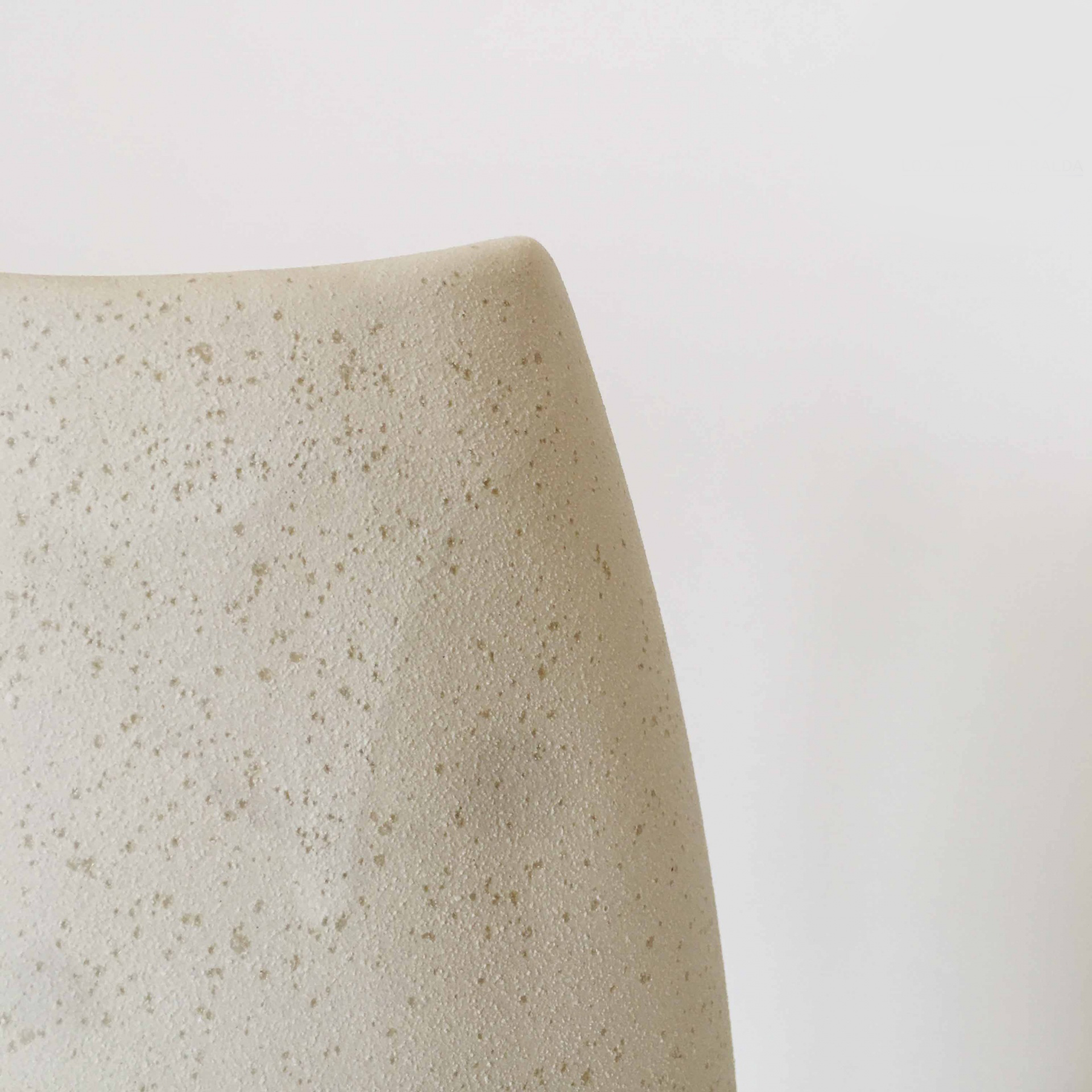 Topo arredondado de vaso bege com textura pontilhada