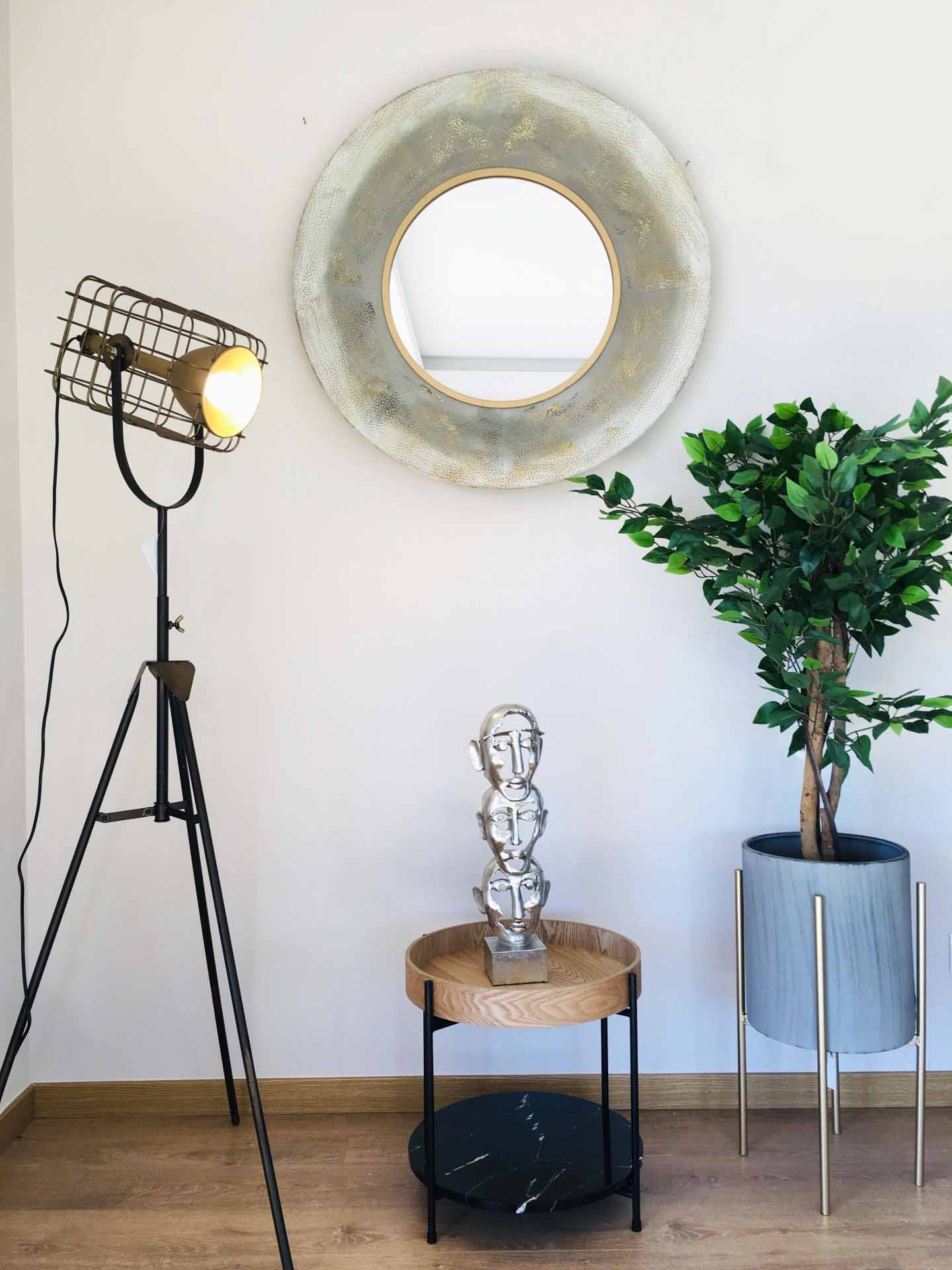 Decoração com candeeiro de pé, espelho redondo, escultura metálica e planta em vaso cinzento