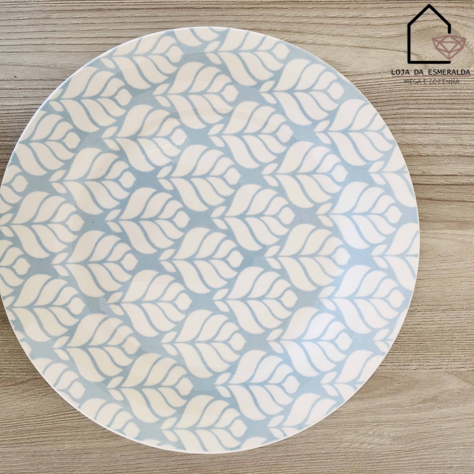 Prato redondo com padrão de folhas brancas sobre fundo azul claro