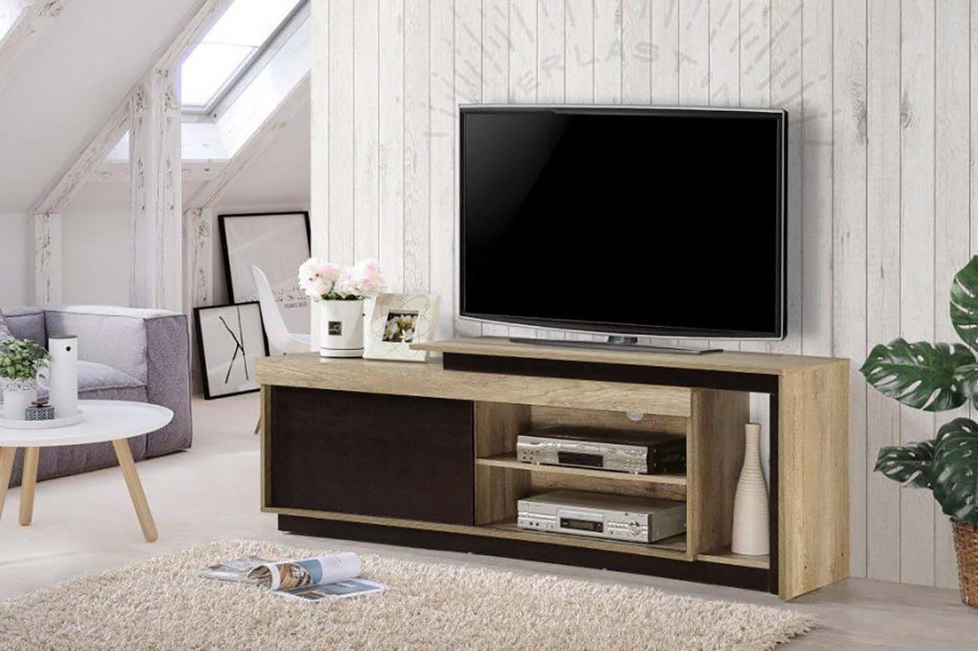 Móvel TV de madeira clara e escura numa sala com parede branca e planta.