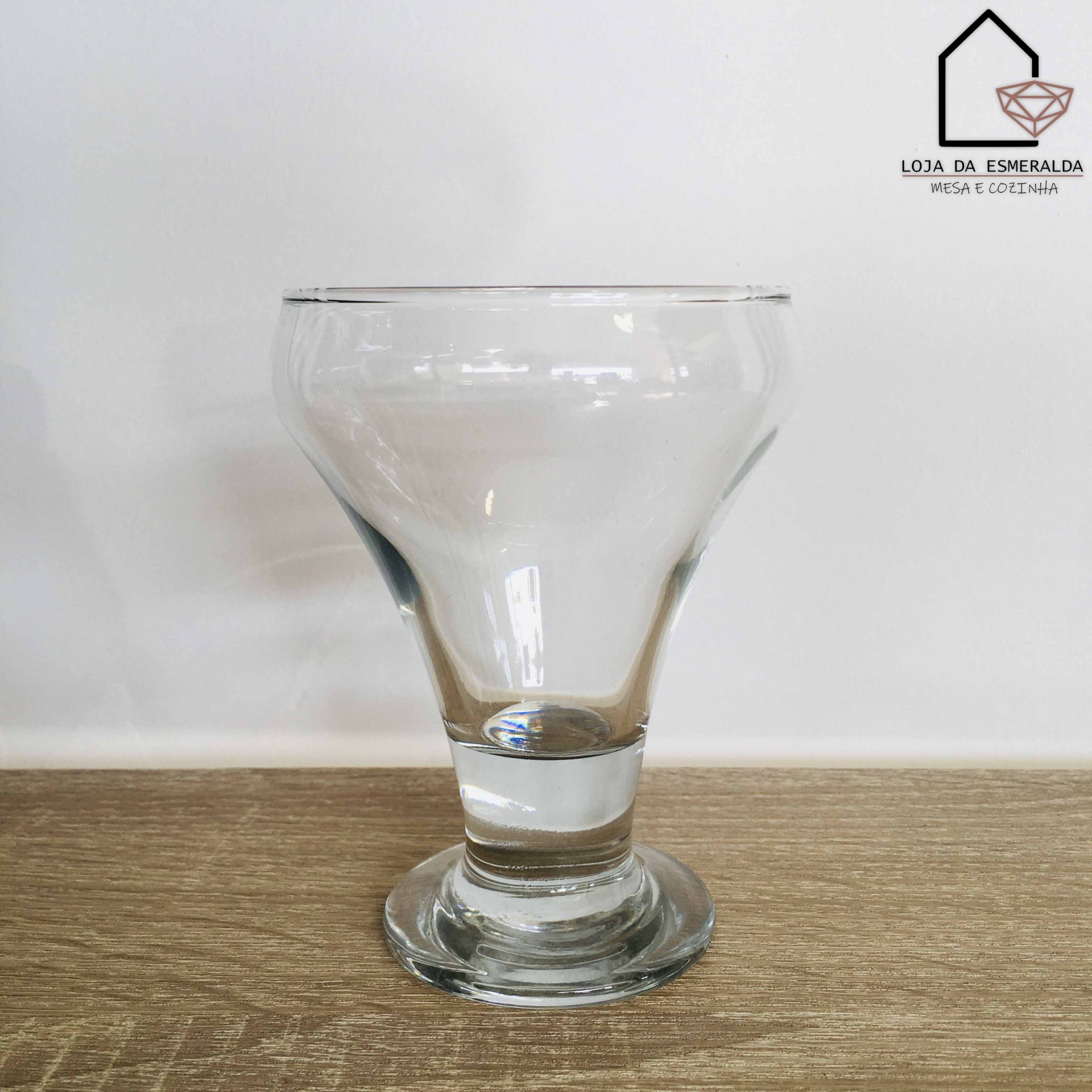 Copo de vidro transparente com base redonda sobre superfície de madeira