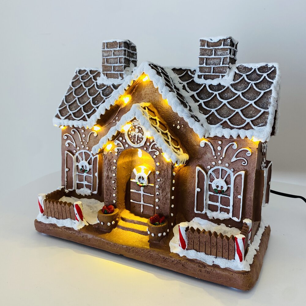 Casa de gingerbread decorativa de Natal com luzes amarelas e detalhes em branco e vermelho