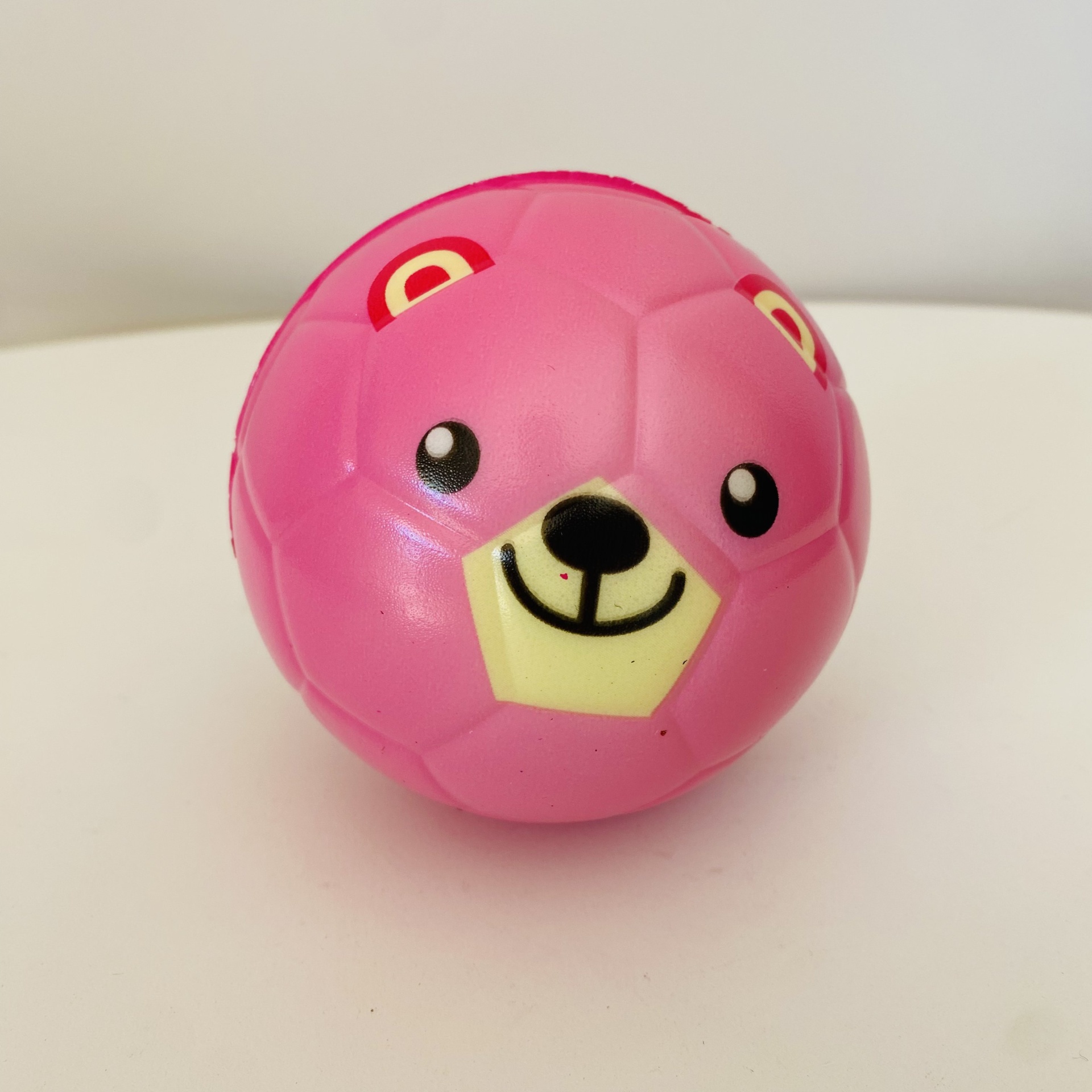 Bola de jogo rosa em formato de urso com rosto sorridente