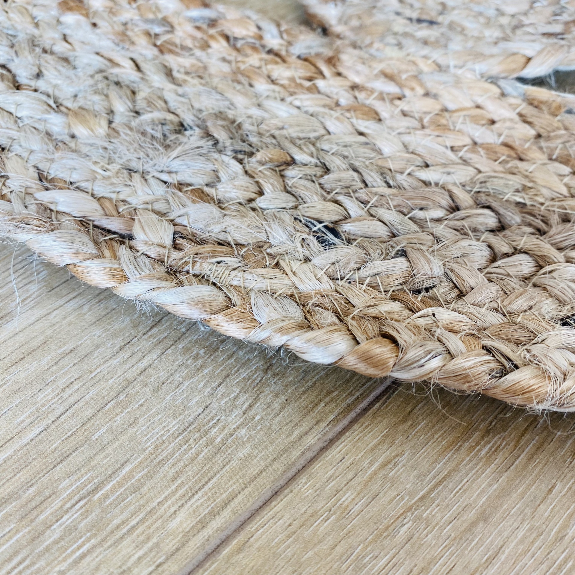 Tapete de fibras naturais entrelaçadas em tons castanhos claro sobre piso de madeira clara