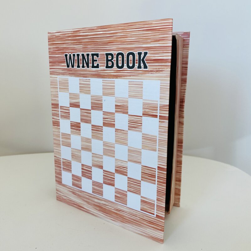 Livro com capa xadrez branco e castanho e texto 'WINE BOOK'