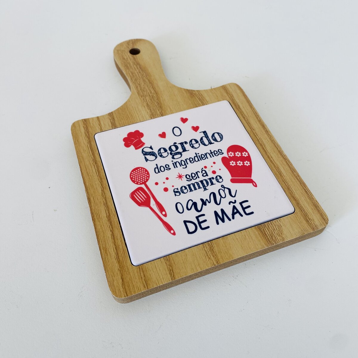 Tábua de cozinha de madeira com azulejo decorativo com texto em português.