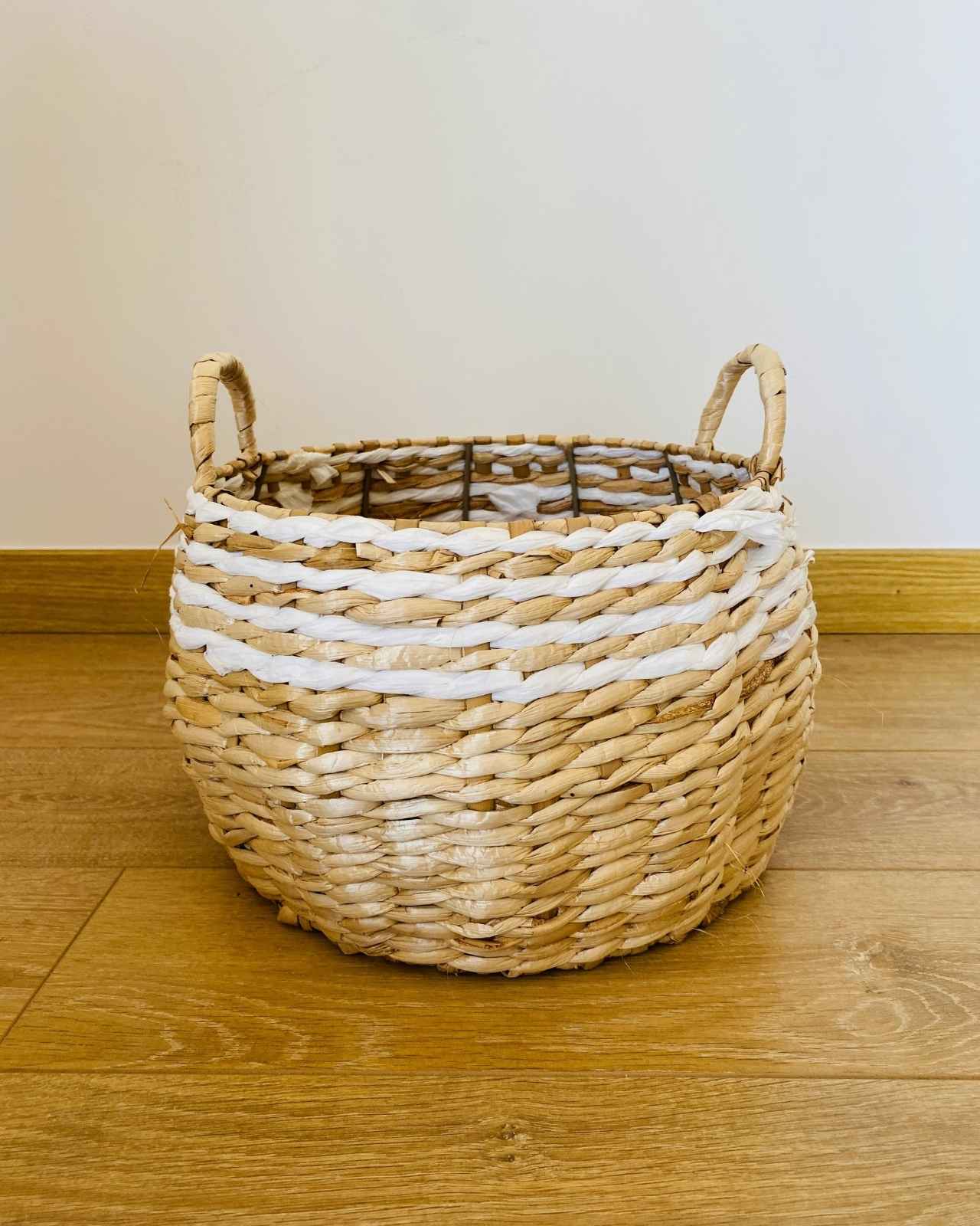 Cesto redondo de palha natural com detalhes brancos e duas alças