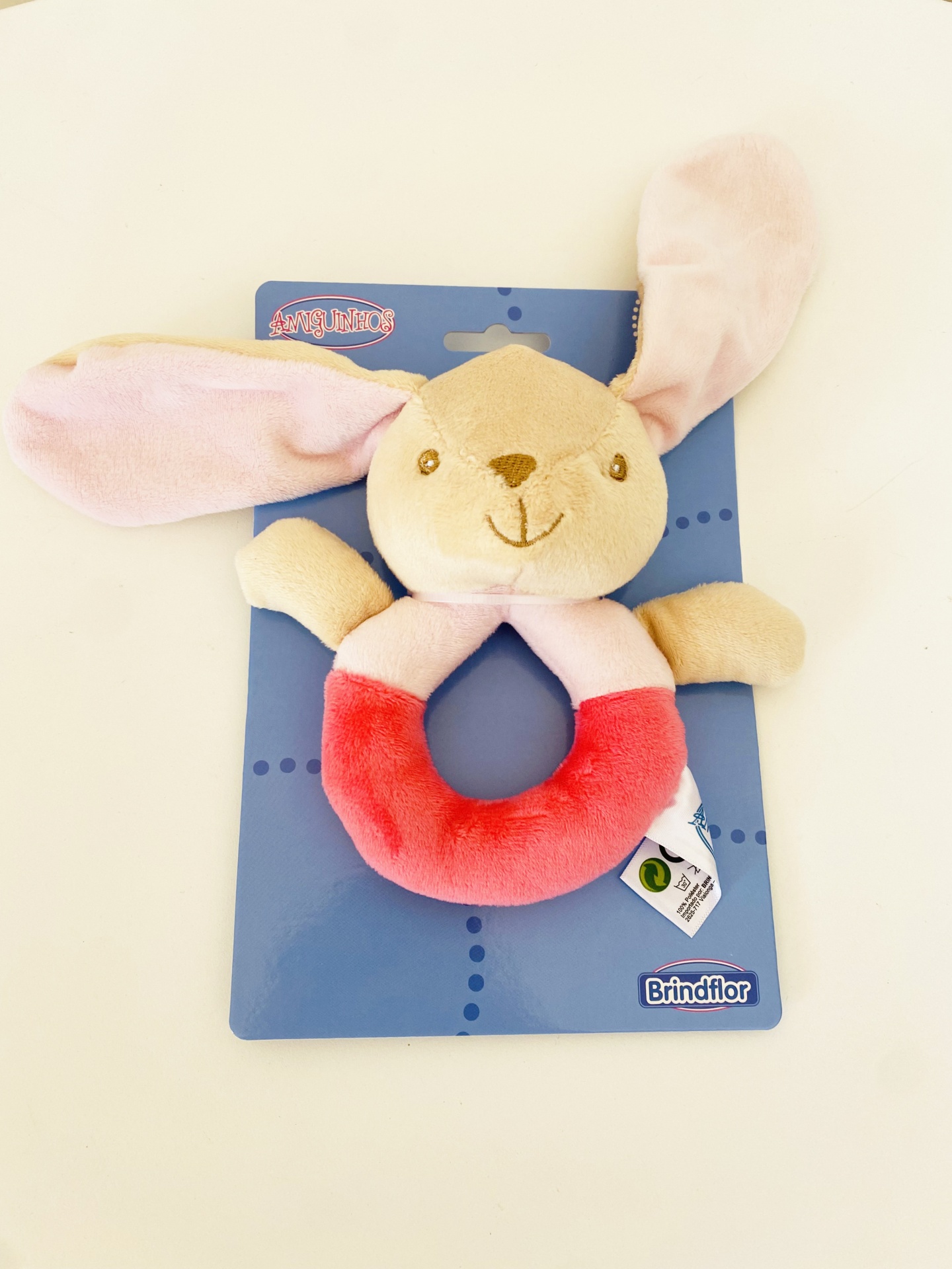 Carrilhão de peluche em forma de coelho colorido numa embalagem azul.