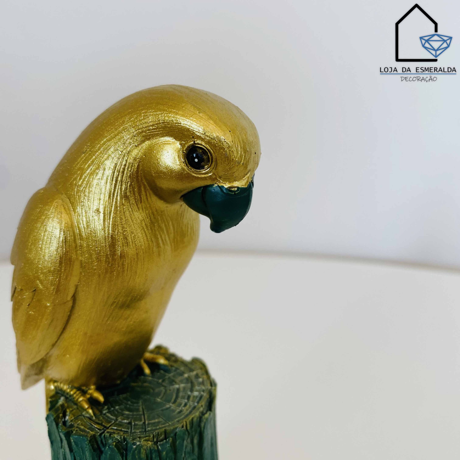 Estátua decorativa pássaro dourado com bico preto sobre tronco verde