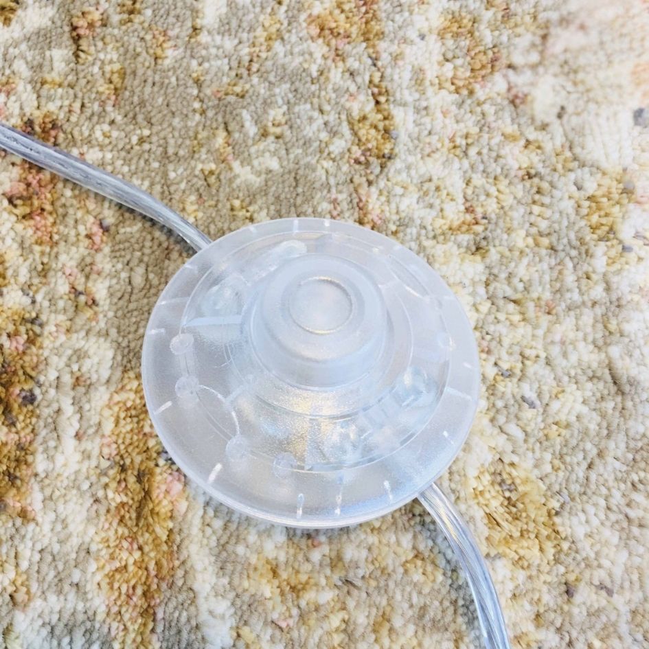 Interruptor circular transparente com cabos sobre tecido bege e castanho.