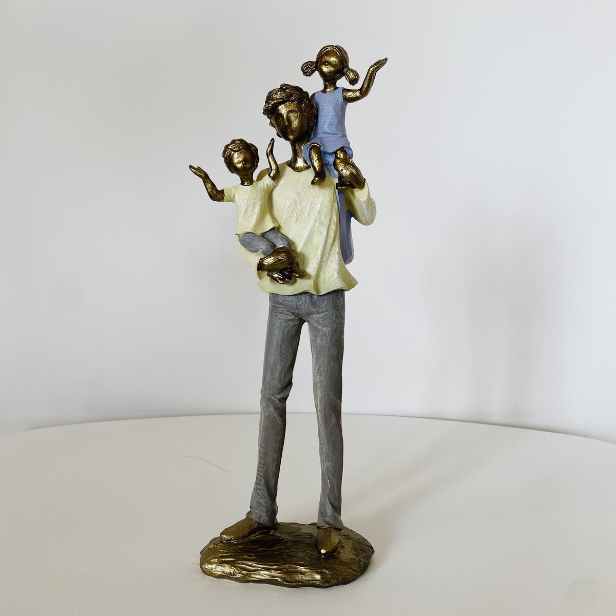 Estátua decorativa de homem com duas crianças nos ombros em metal pintado