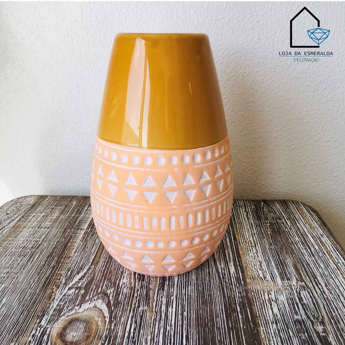 Vaso de cerâmica amarelo e salmão com padrão geométrico sobre mesa de madeira