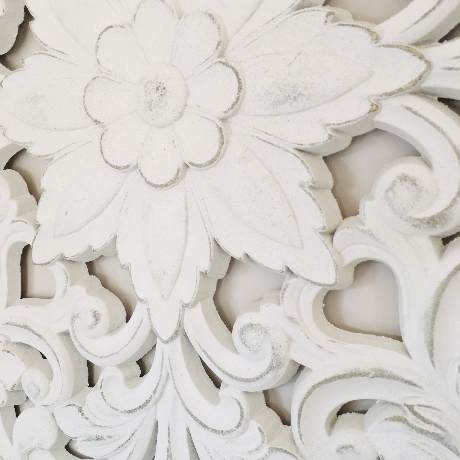 Relevo em madeira branca com padrão floral e arabescos