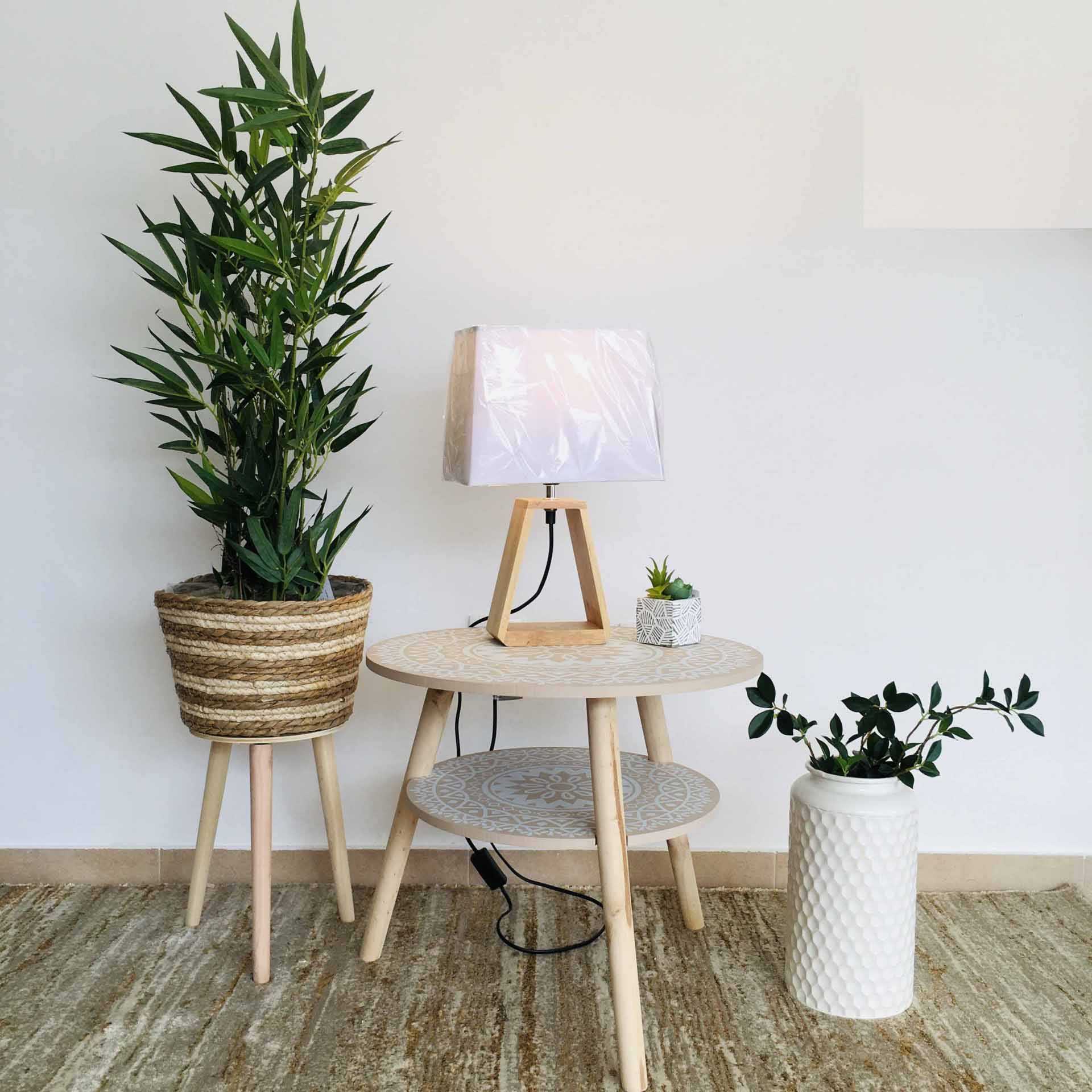 Conjunto de móveis e plantas decorativas em ambiente interior com mesa de madeira clara e luminária
