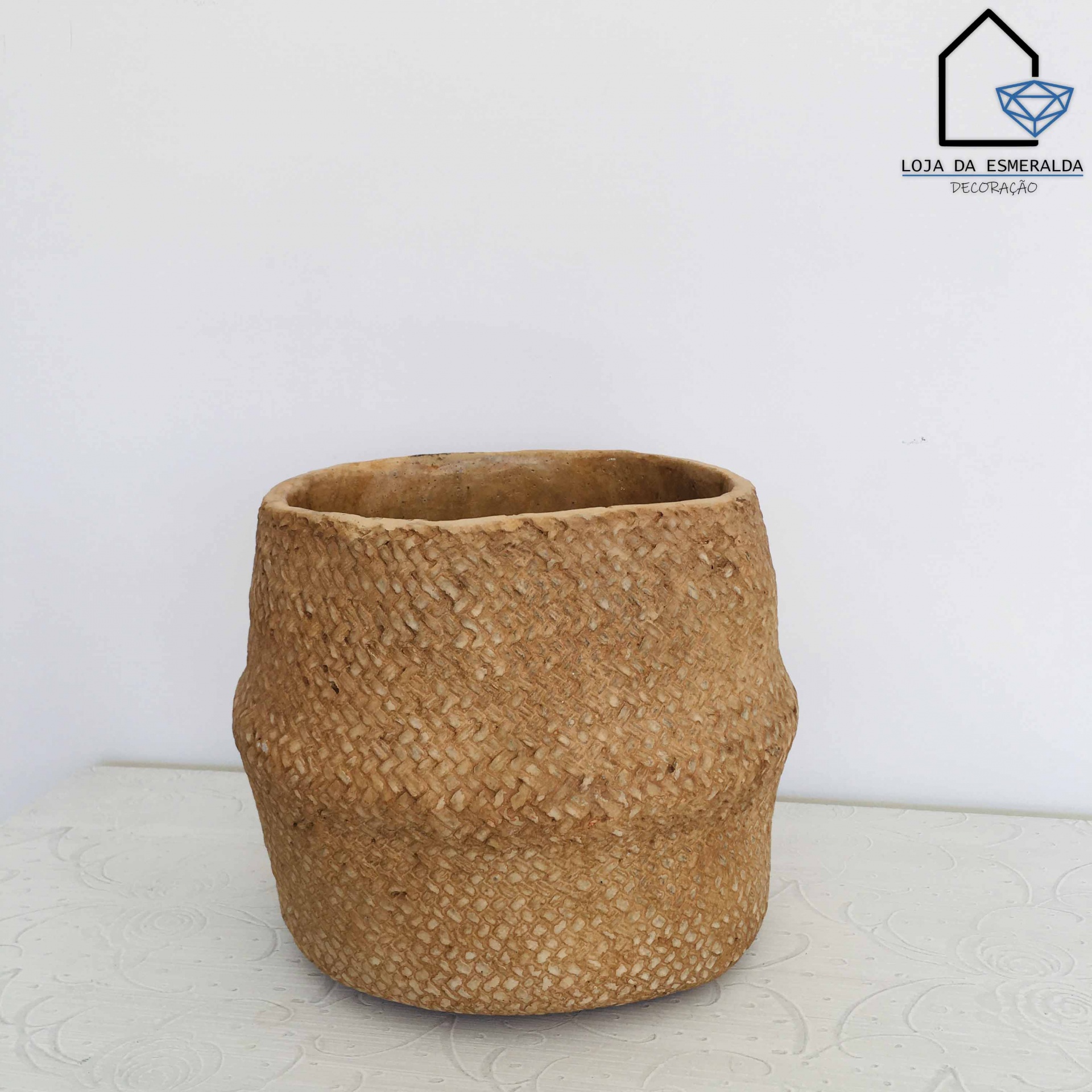 Cesto trançado rústico castanho claro em superfície branca