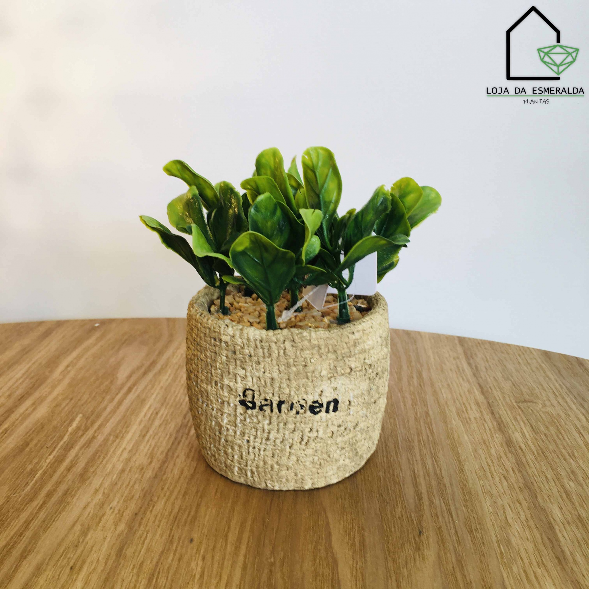 Vaso com planta artificial em vaso texturizado sobre mesa de madeira