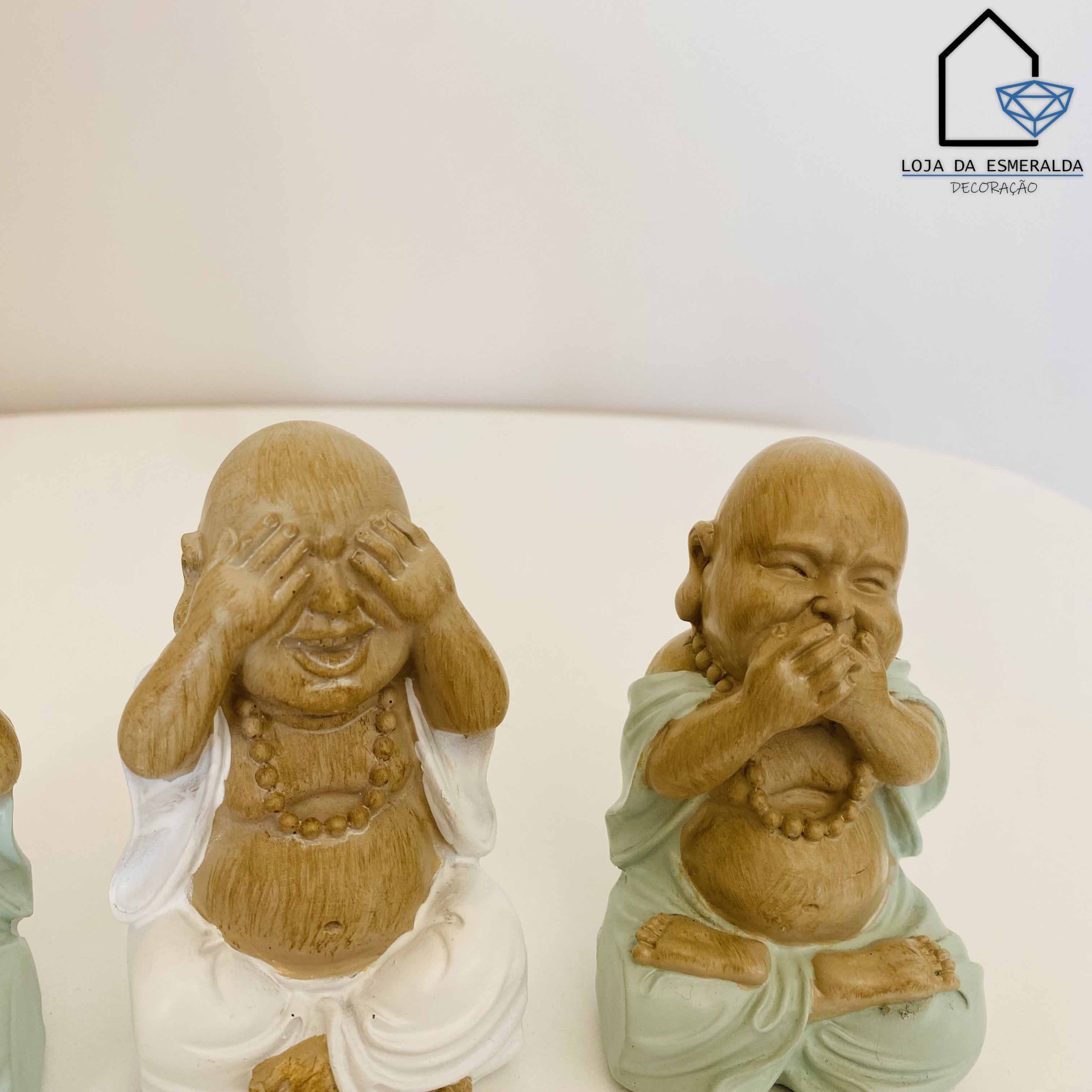 Estatuetas de budas sorridentes em madeira e cerâmica, vestindo branco e verde.
