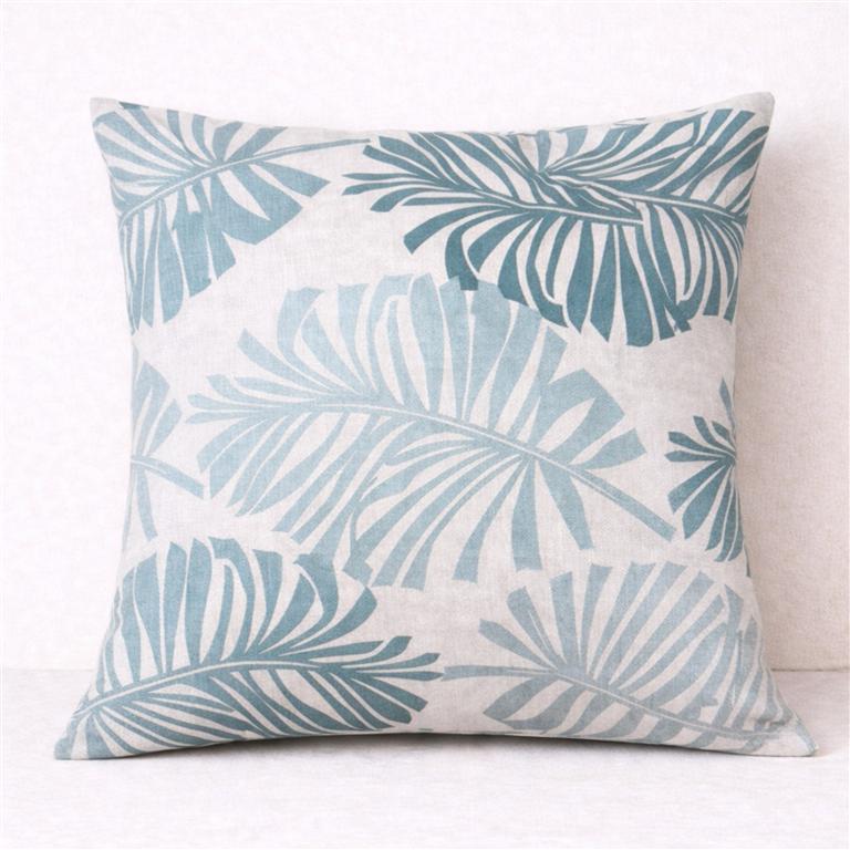 Almofada com padrão de folhas azuis sobre fundo cinzento claro