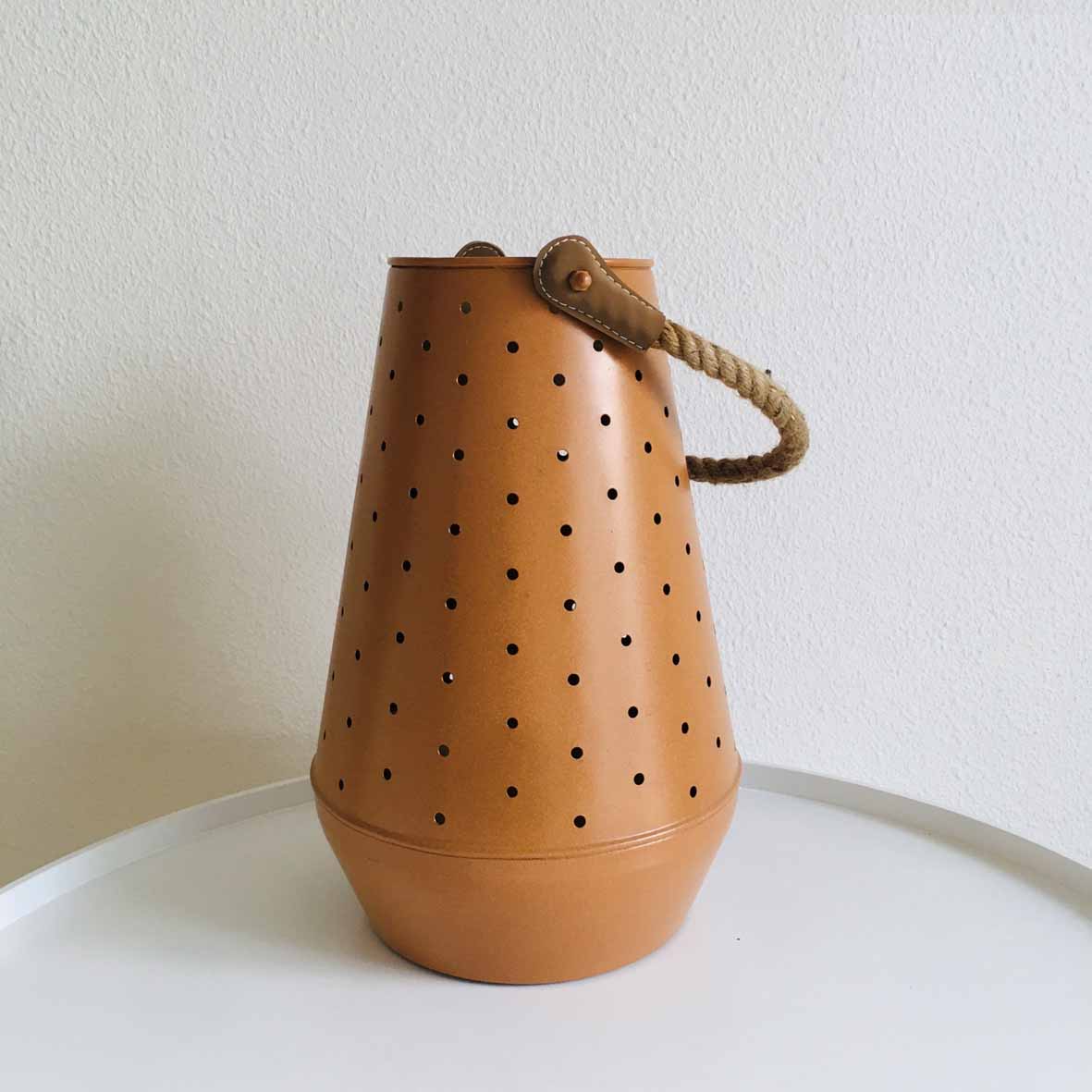 Lanterna de metal castanho com perfurações e alça de corda