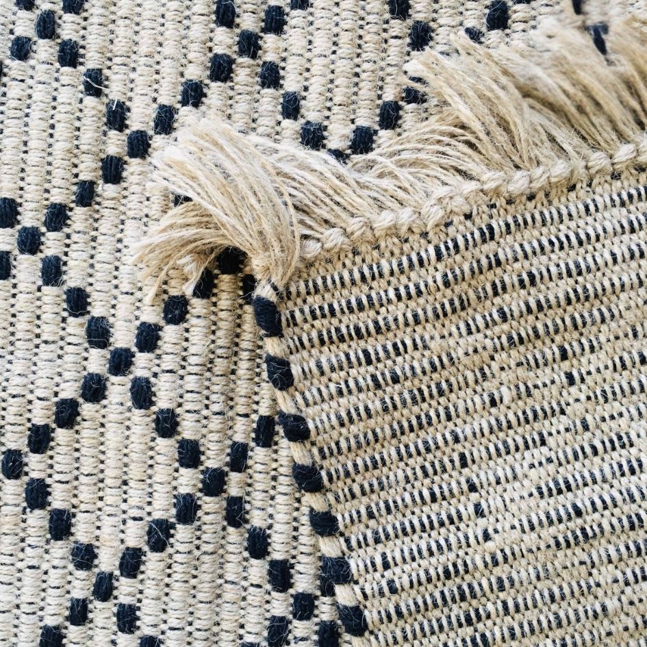 Tapete tecido bege com padrão geométrico preto e franjas