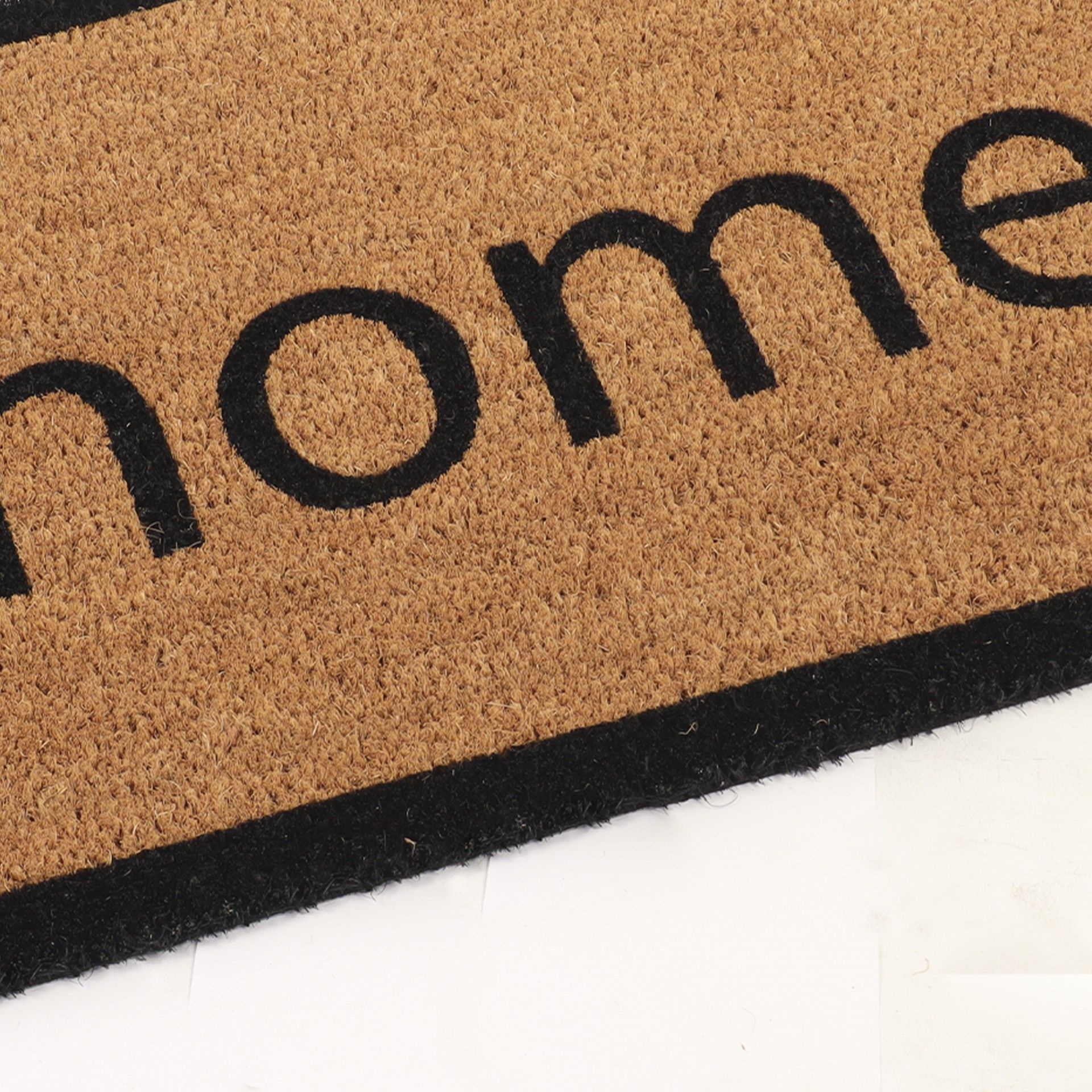 Tapete de entrada castanho claro com a palavra 'home' a preto