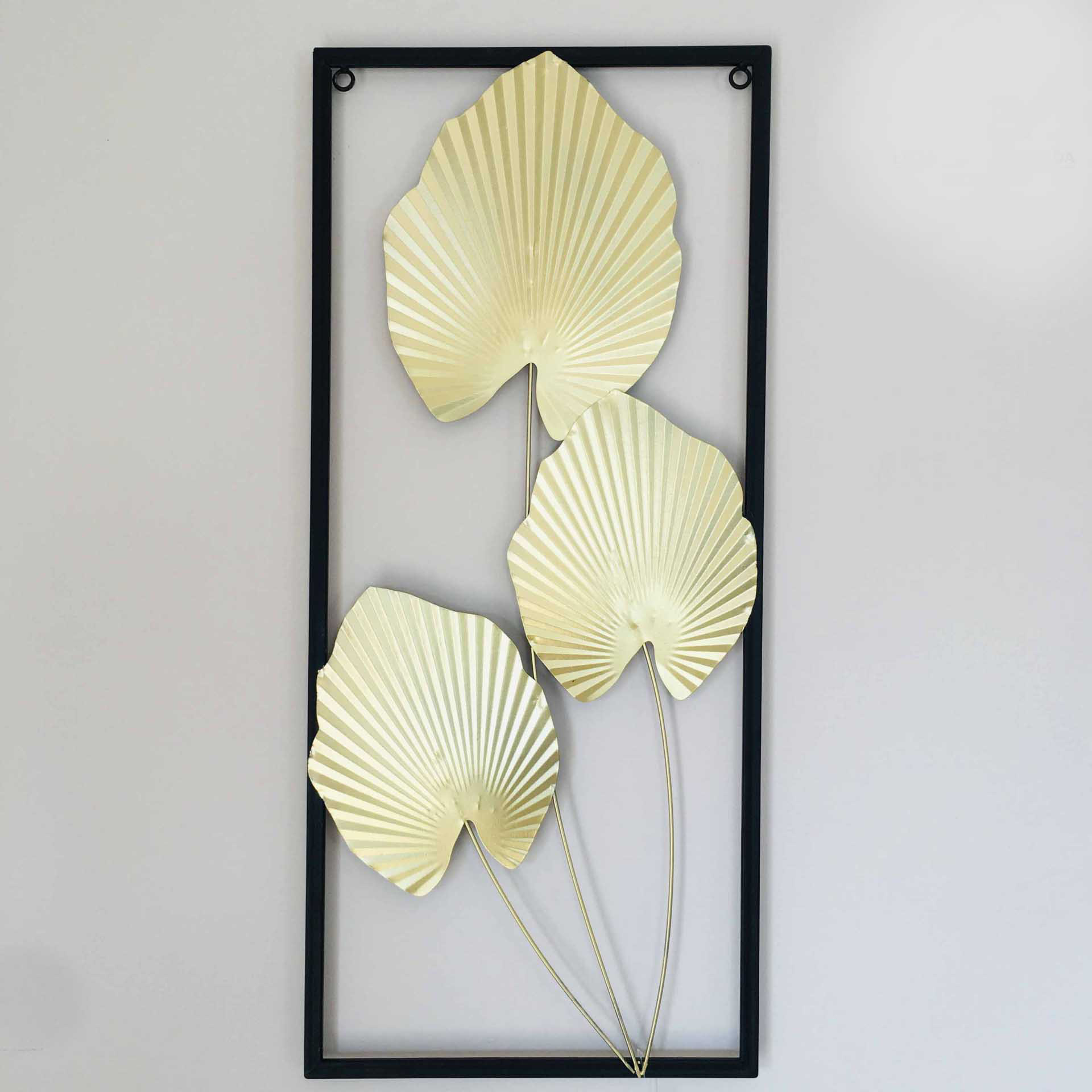Decoração de parede com três folhas metálicas douradas dentro de moldura preta