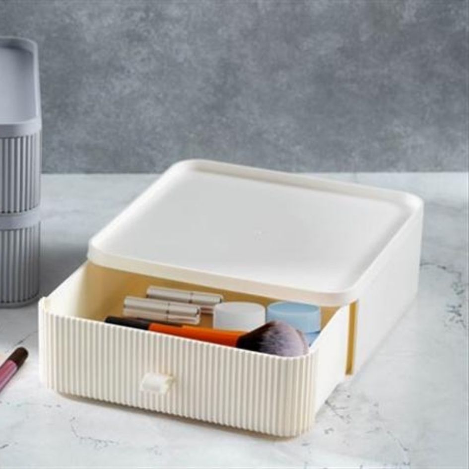 Caixa organizadora creme com gaveta aberta contendo pincéis de maquilhagem.