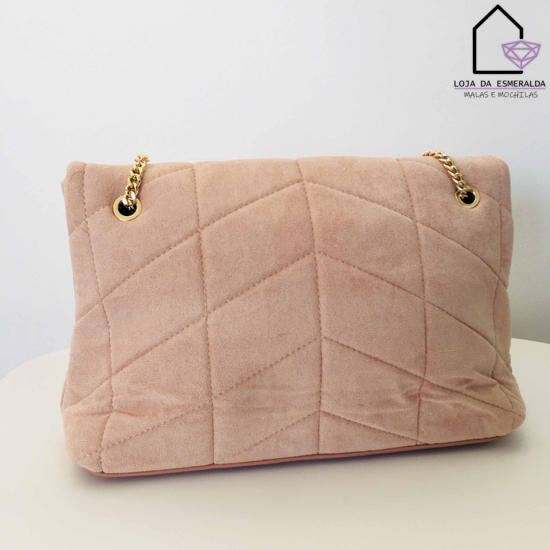 Mala bege claro aveludada com padrão geométrico e correntes douradas sobre superfície branca