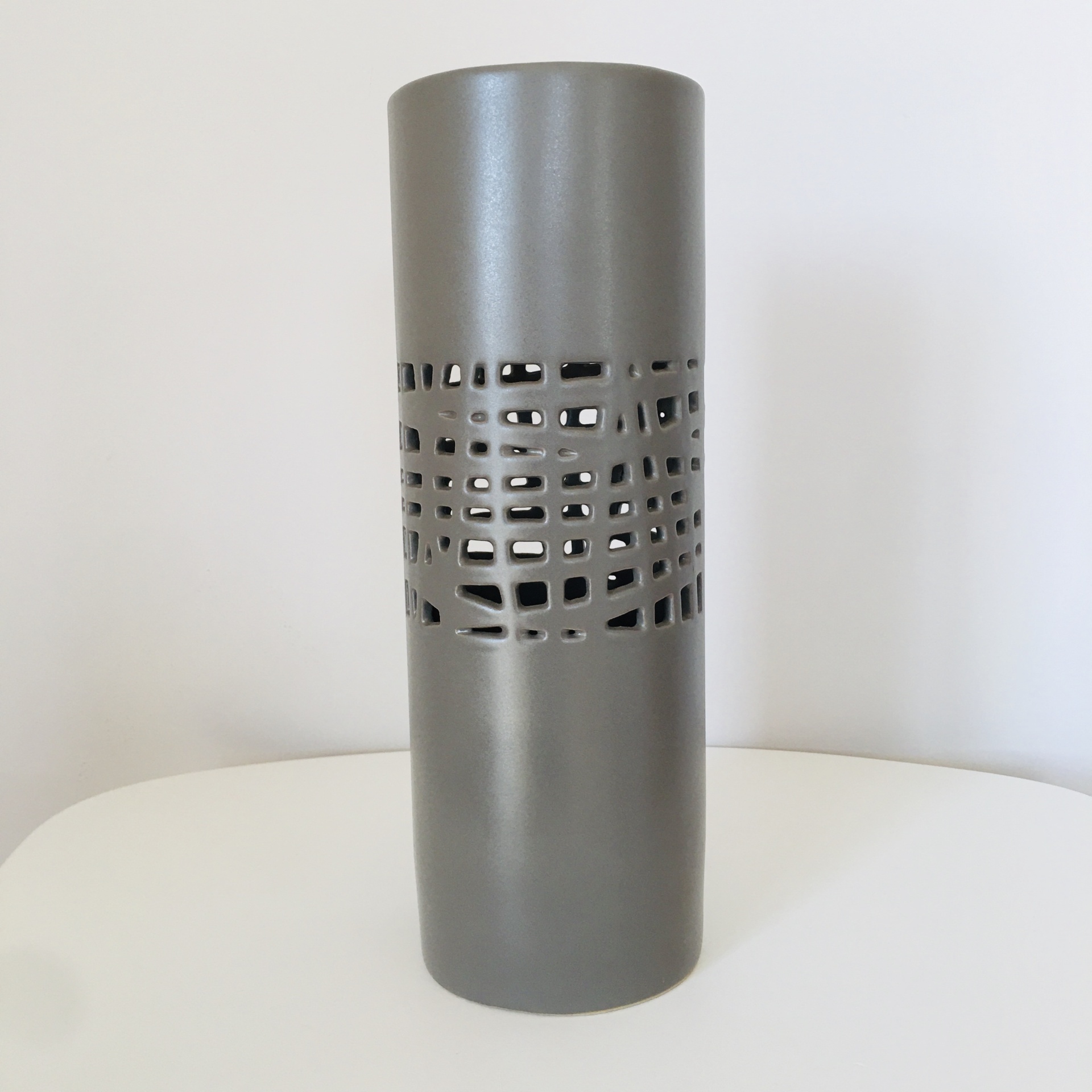Vaso cilíndrico cinzento com recortes geométricos