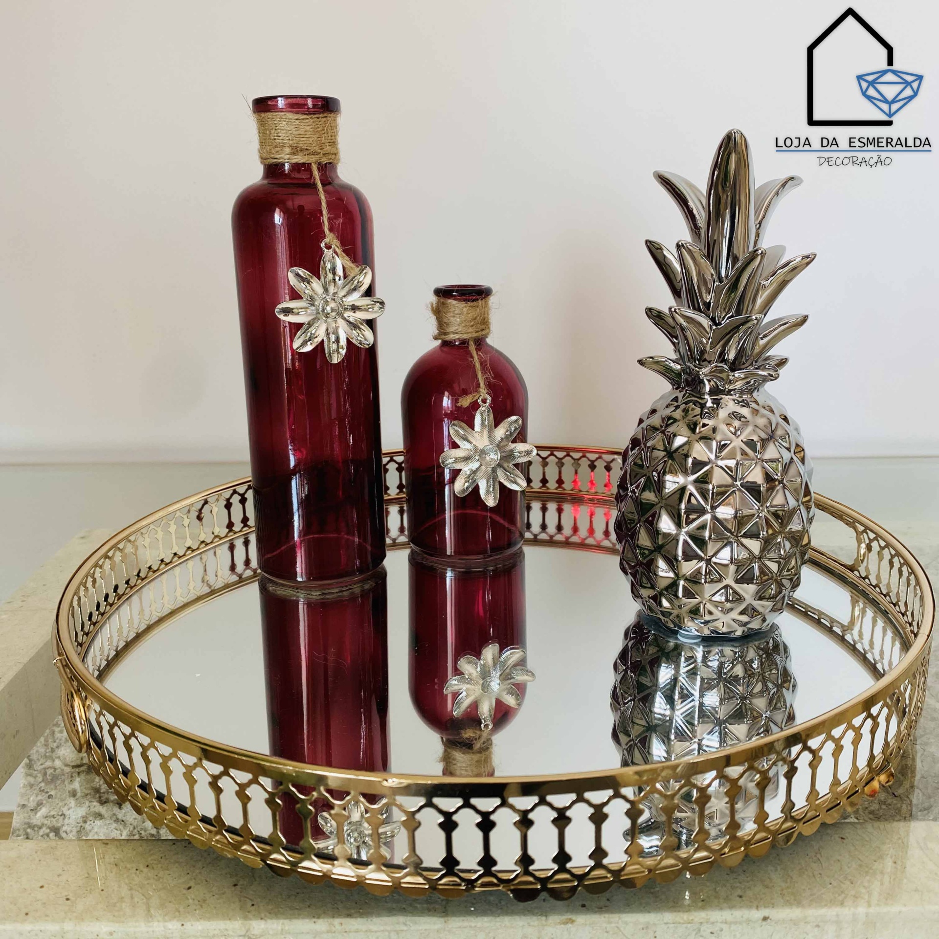 Bandeja dourada com garrafas vermelhas e abacaxi decorativo prateado