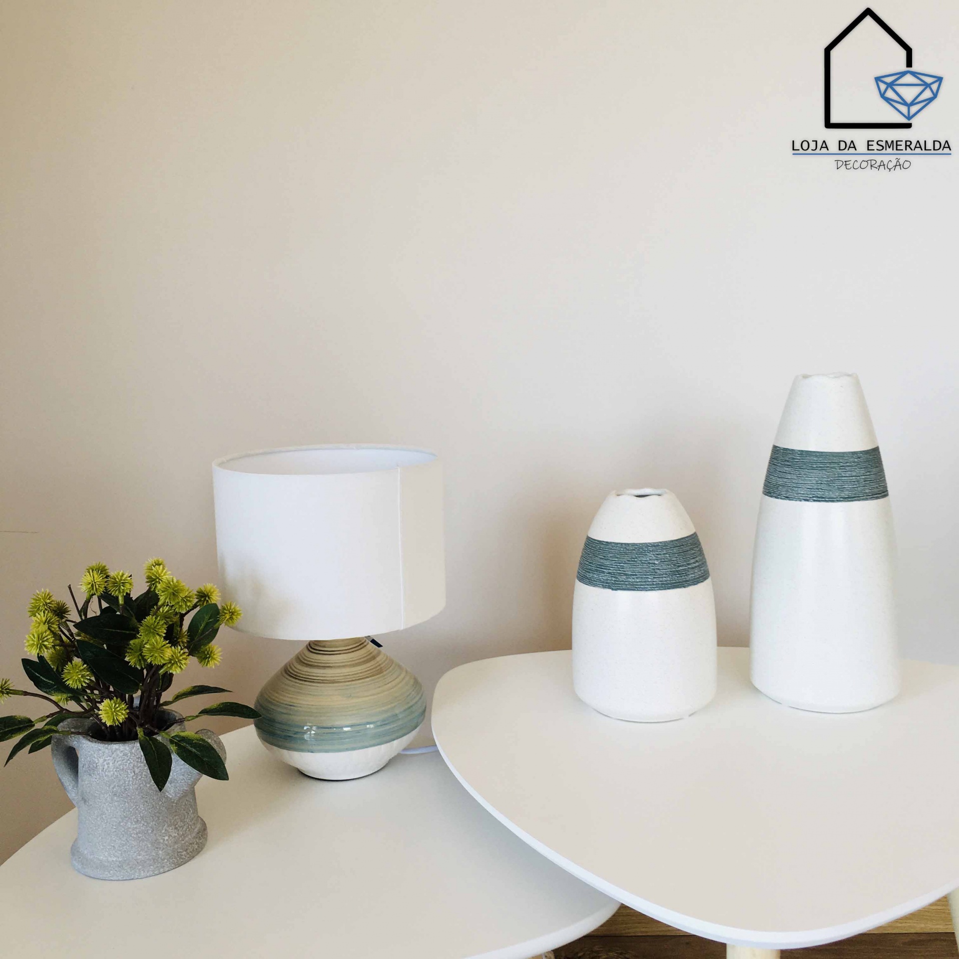 Conjunto de decoração com vasos cerâmicos, candeeiro de mesa e vaso com flores em mesas brancas