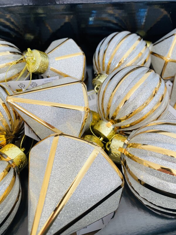 Decorações de Natal prateadas e douradas em formas variadas numa caixa preta