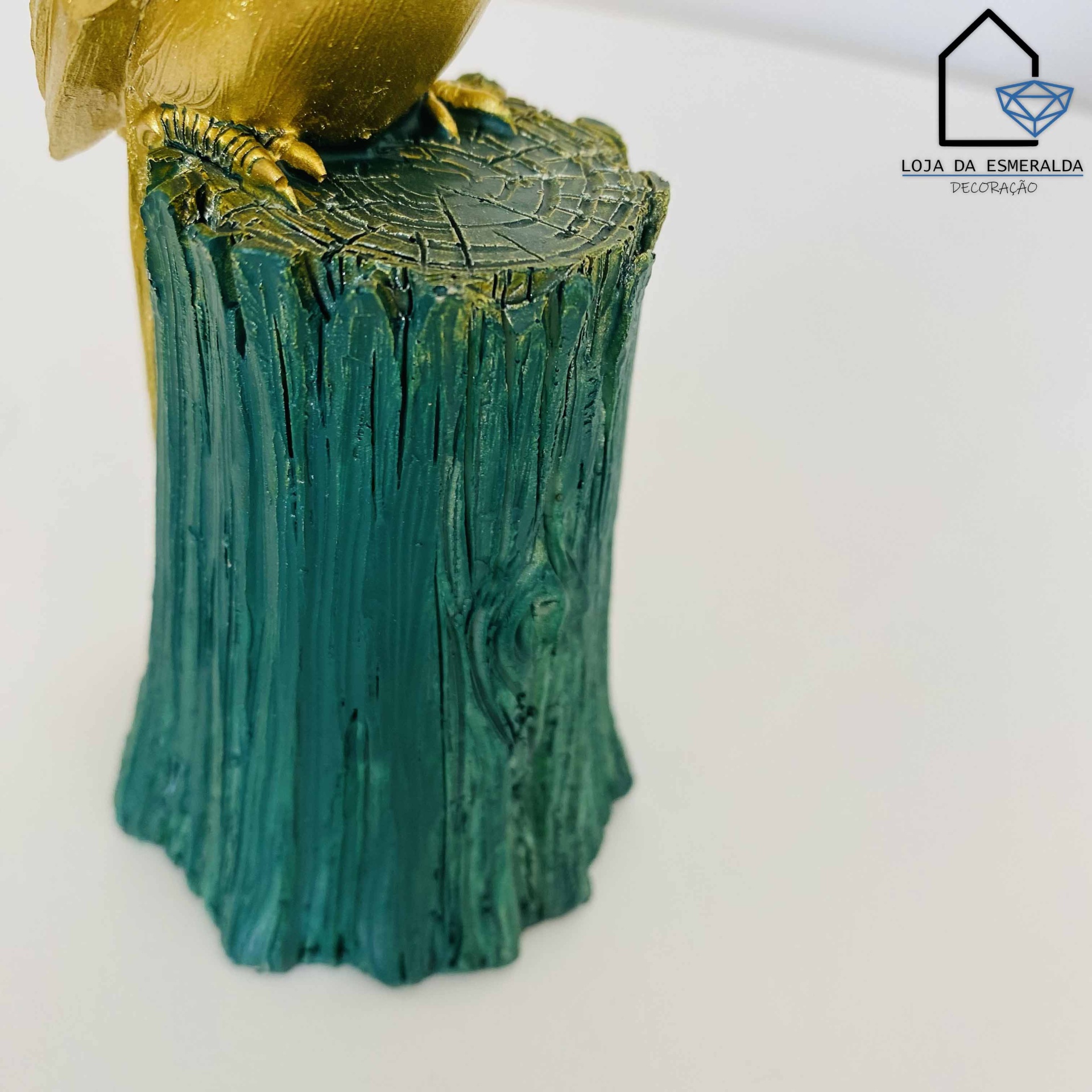 Escultura com base de tronco de árvore verde e patas douradas de ave