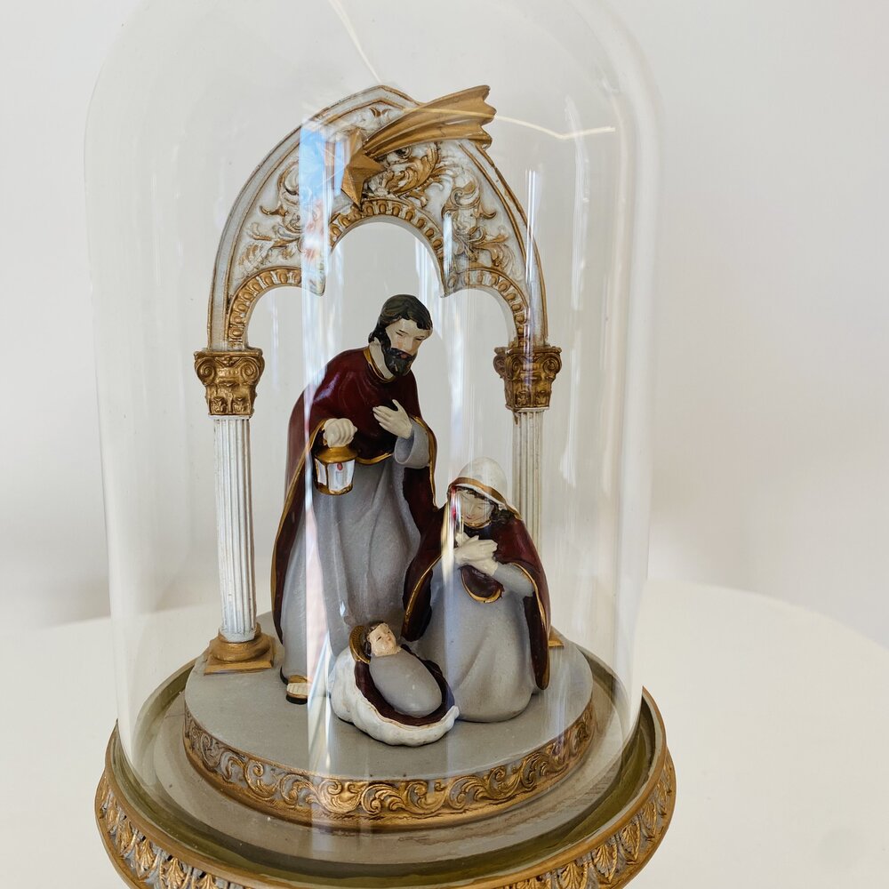 Presépio pequeno dentro de uma cúpula de vidro com base dourada