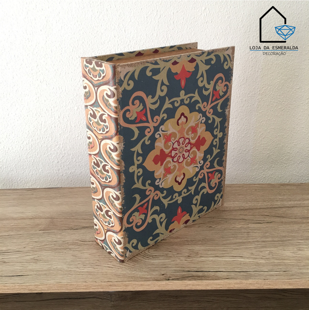 Livro decorativo com padrão floral clássico em várias cores sobre mesa de madeira.