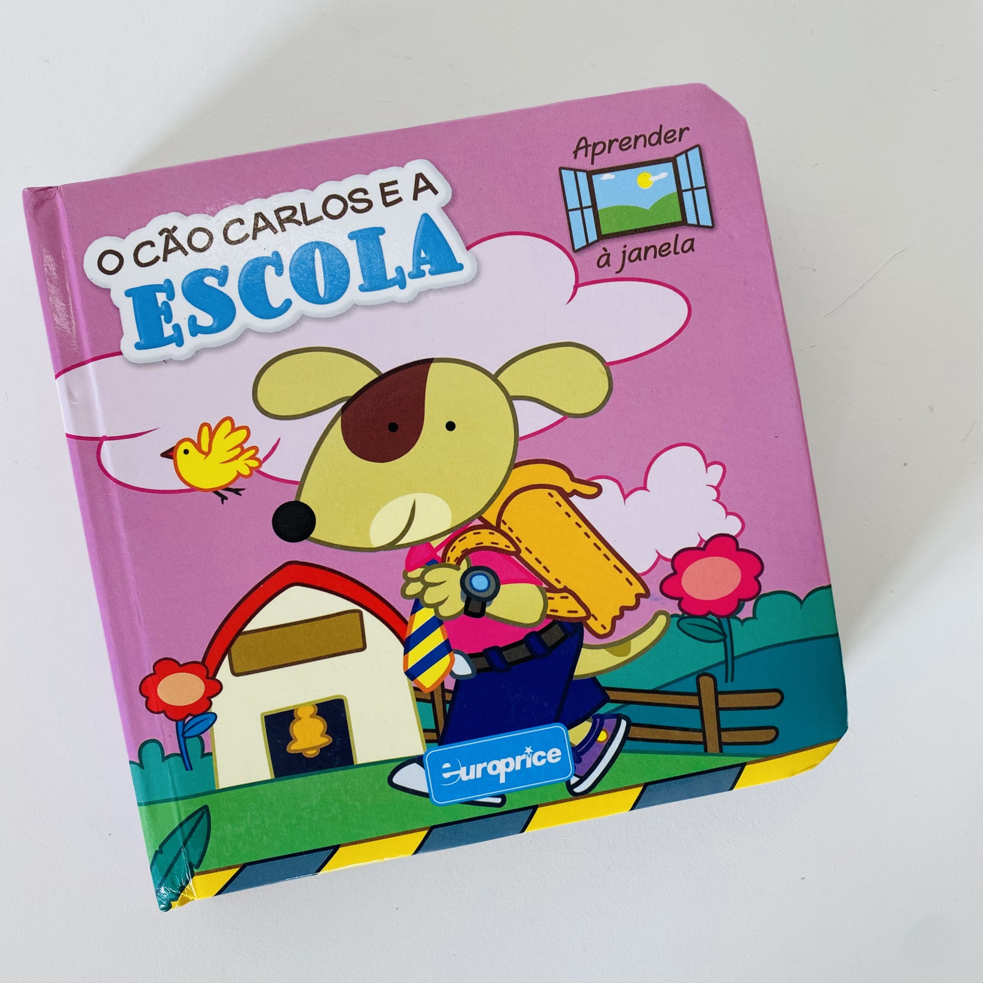 Capa de livro infantil O Cão Carlos e a Escola com cão, pássaro e escola desenhados