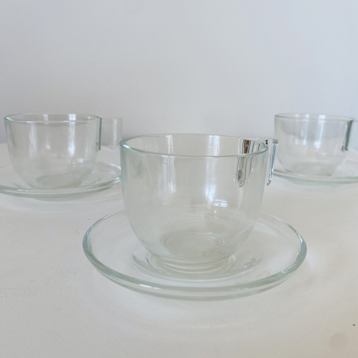 Três chávenas de vidro transparentes com pires