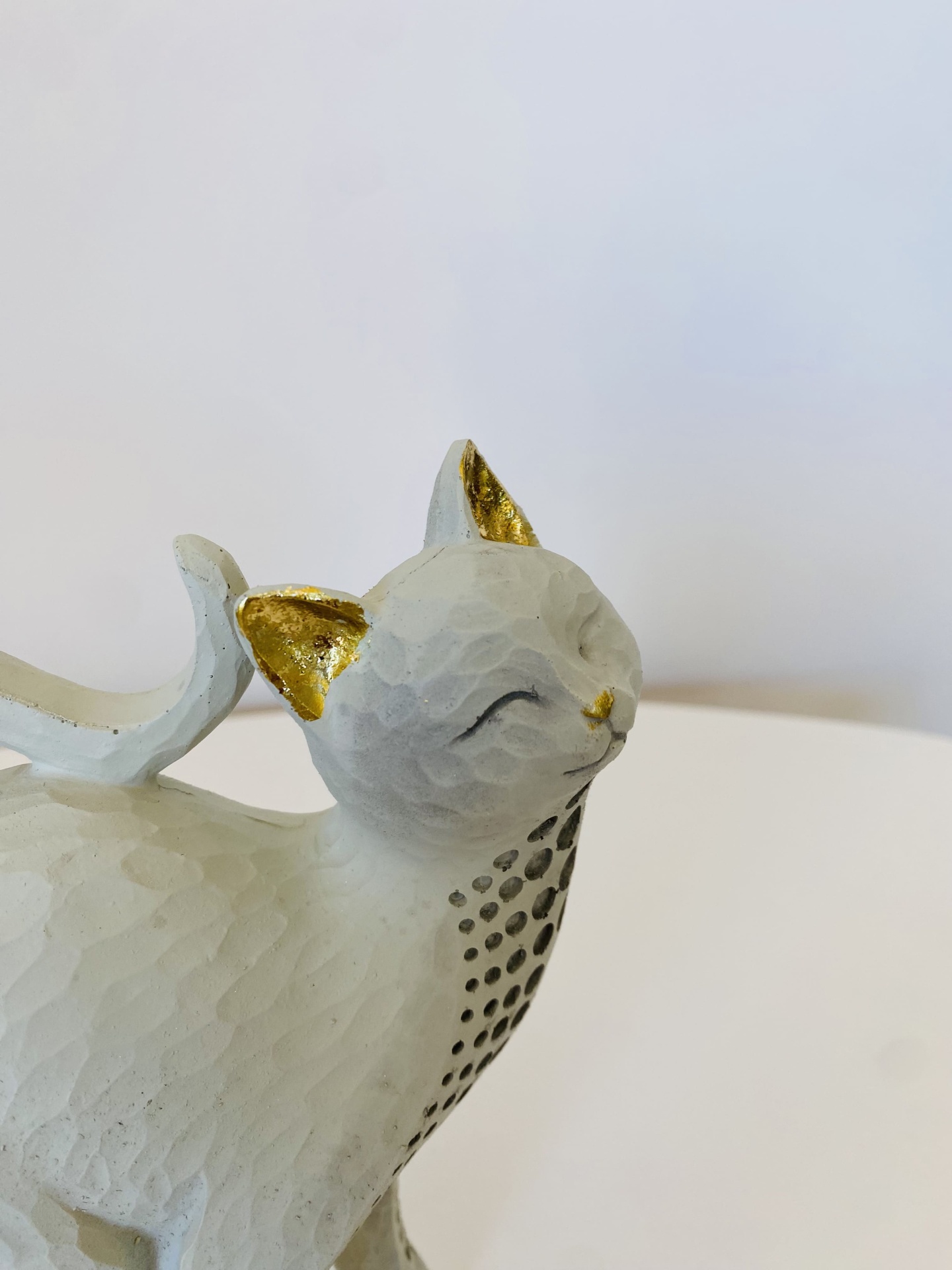 Escultura decorativa de gato branco com detalhes dourados nas orelhas e nariz