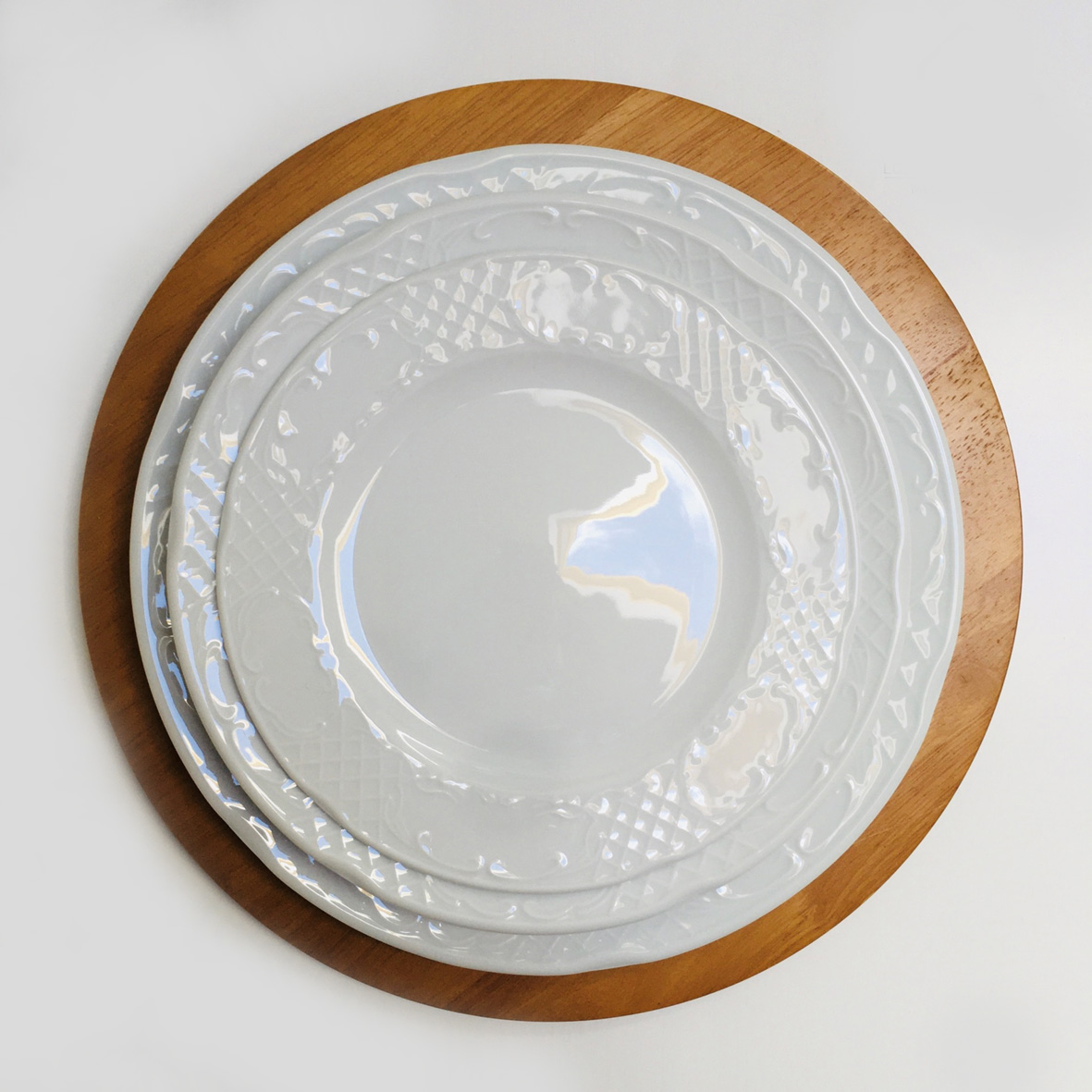 Conjunto de pratos brancos com padrões em relevo sobre base de madeira