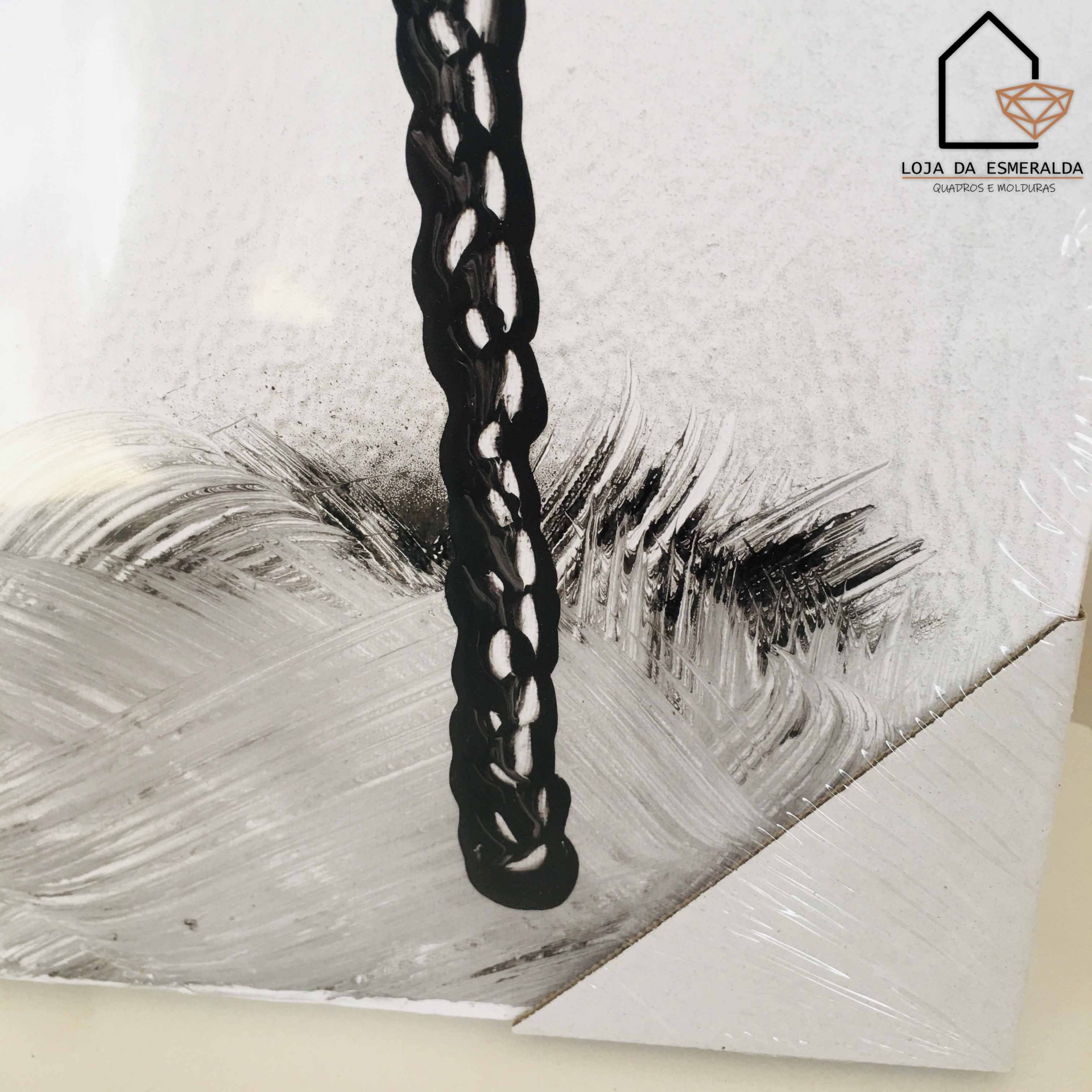 Quadro com ramo de folhas preto e cinza, corda preta, e logótipo da loja no canto superior direito