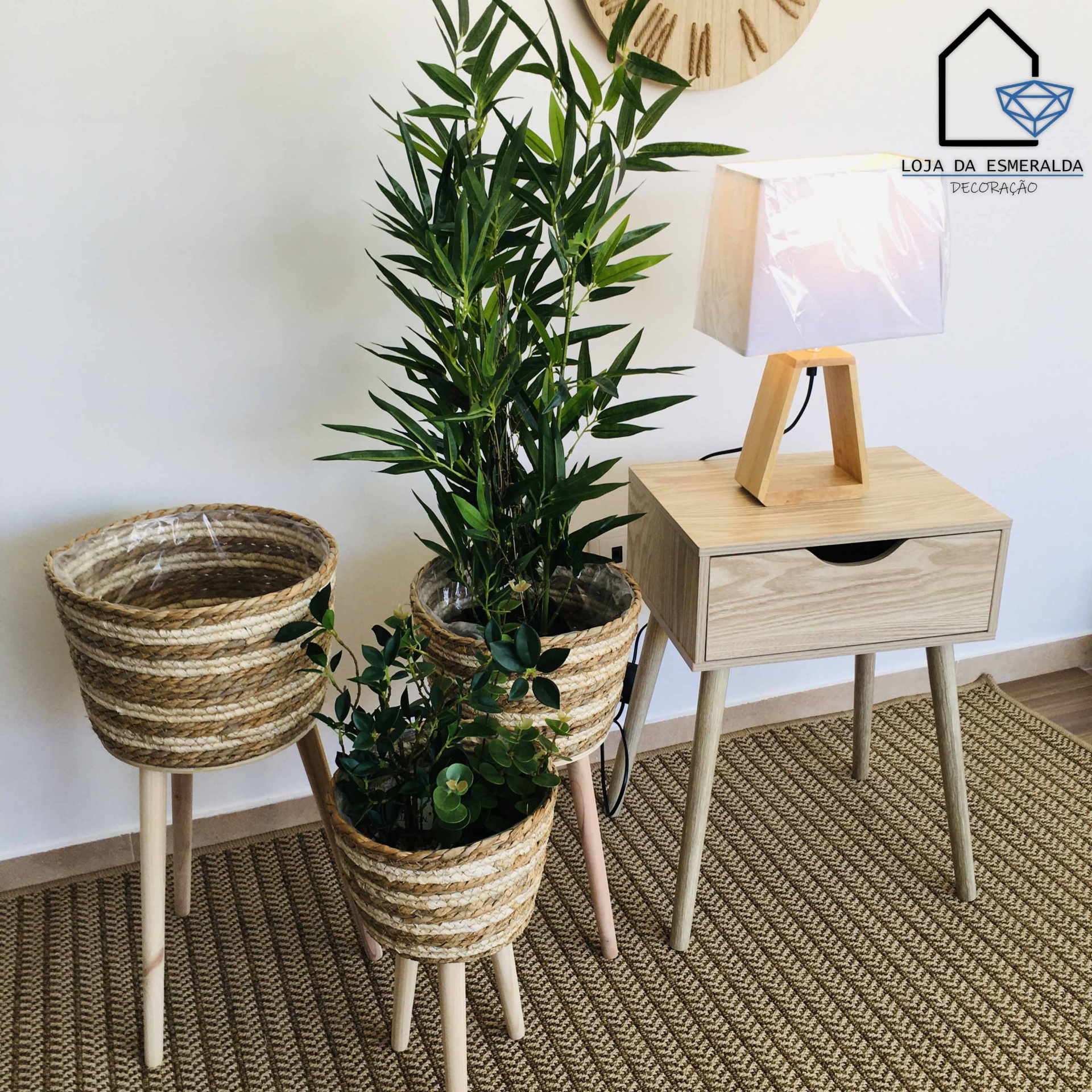 Três floreiros de palha com plantas e mesa de cabeceira com lâmpada