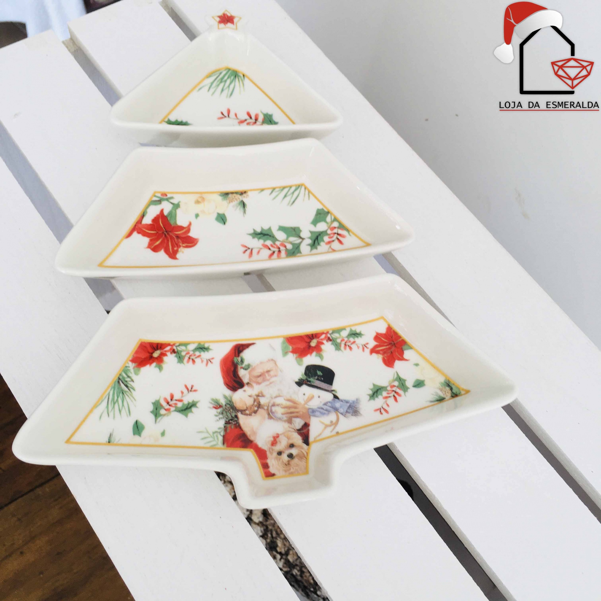 Três pratos de porcelana natalícios em forma de árvore de Natal com decoração festiva colorida.