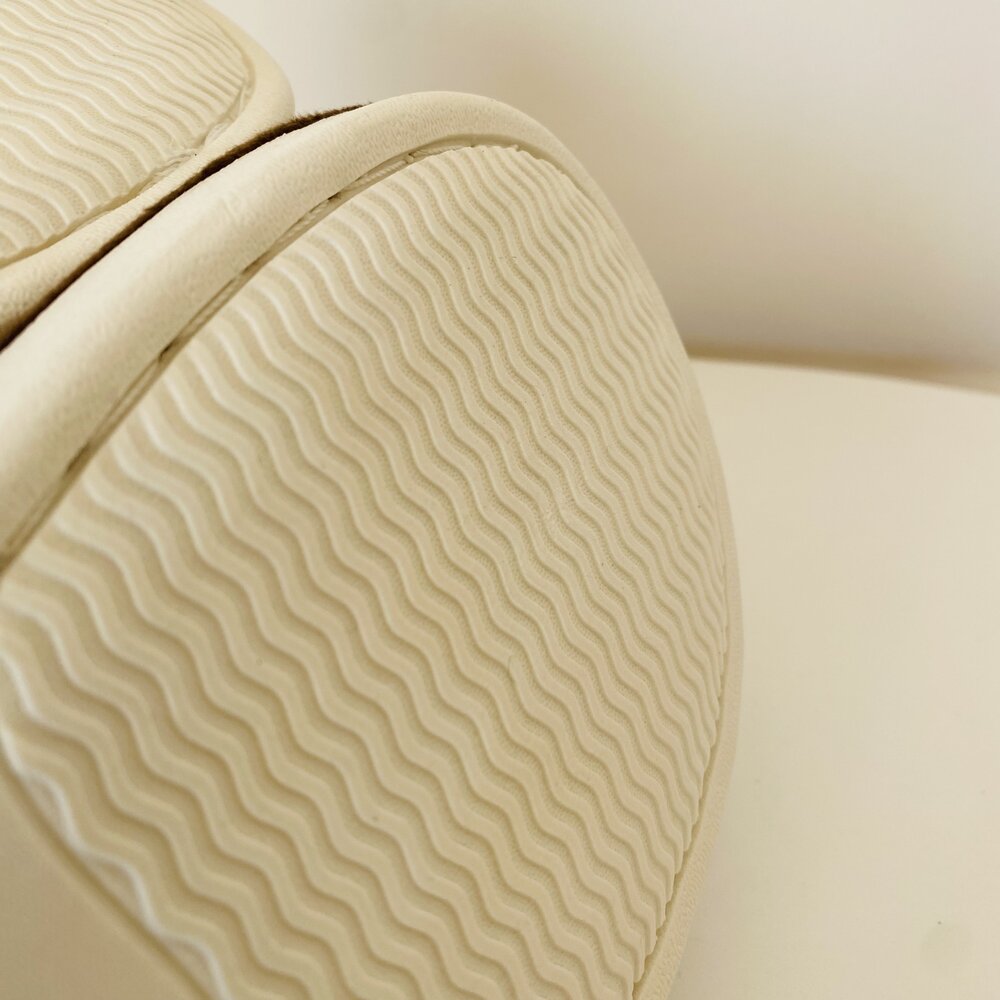 Sola de calçado bege com padrão ondulado em fundo neutro