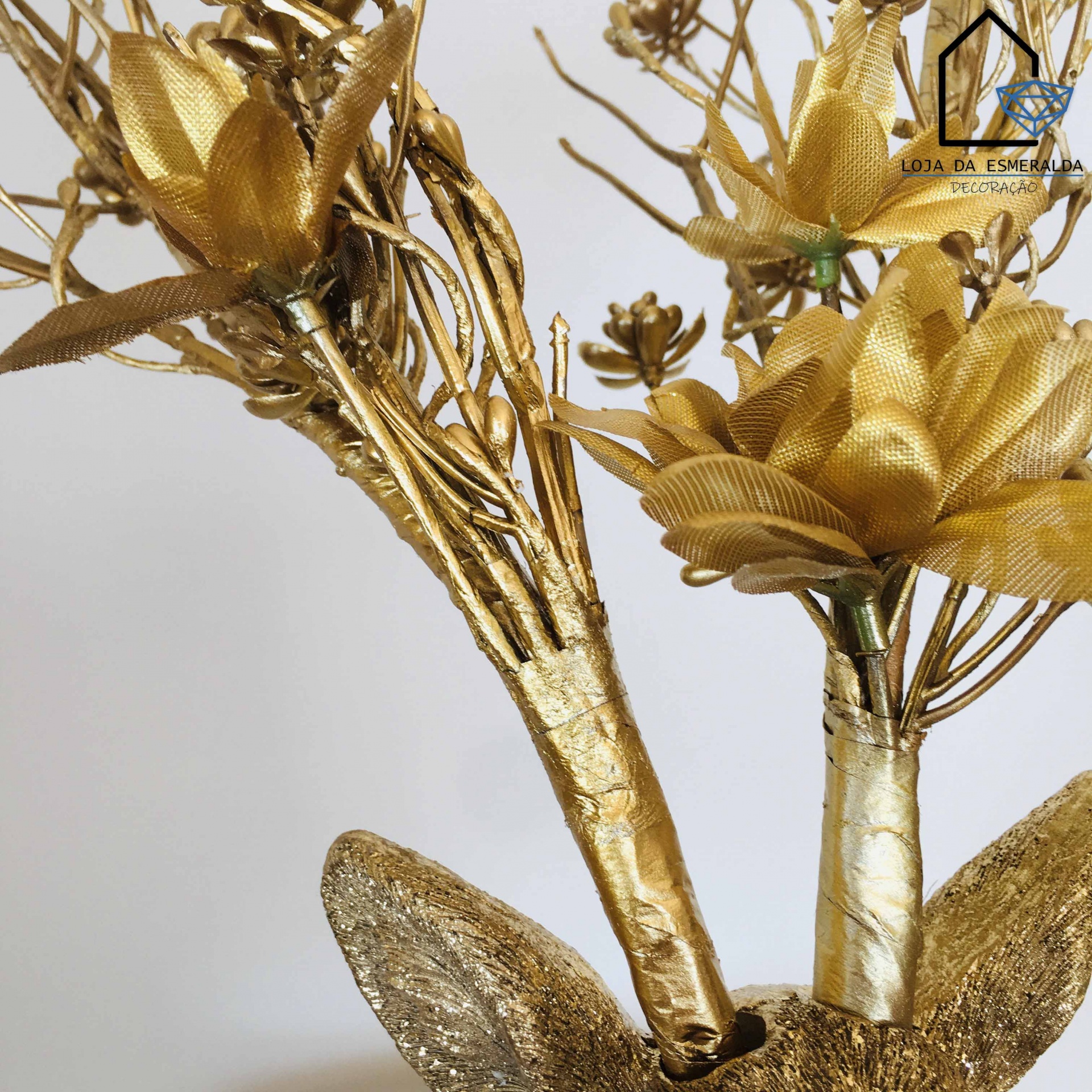 Ramo decorativo dourado com flores de tecido e ramos metálicos em fundo claro