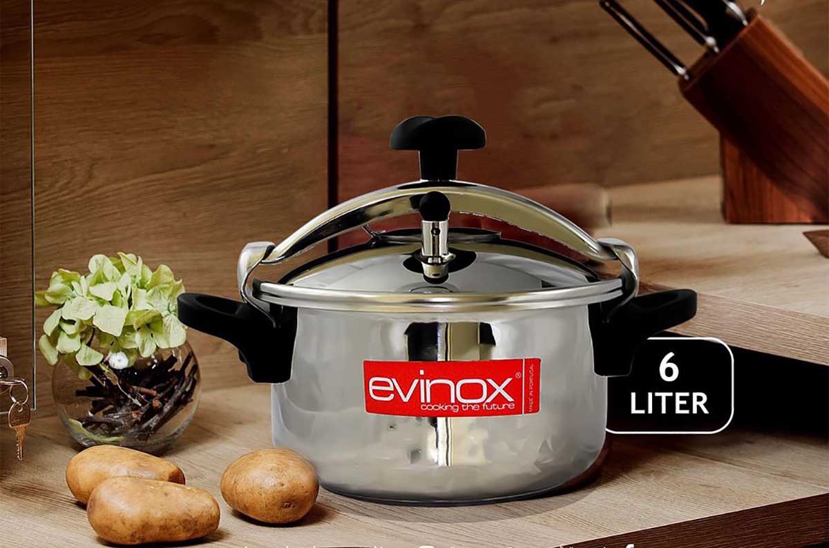 Panela de pressão inox 6 litros sobre bancada de cozinha com batatas e planta