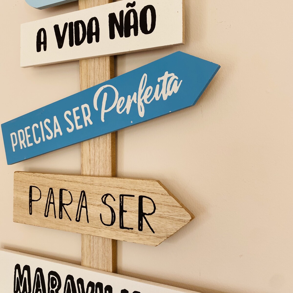 Placa decorativa de madeira com setas e textos em português