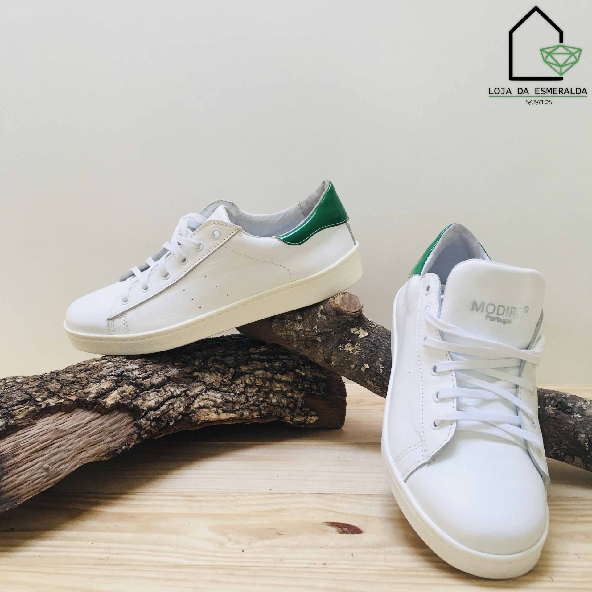 Ténis brancos com pormenores verdes sobre troncos de madeira